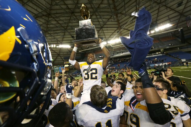 Bellevue running back Budda Baker (32) celebrates with the Class 3A high school football championship trophy, Friday, Dec. 6, 2013, after Bellevue beat Eastside Catholic 52-20, in Tacoma, Wash. (AP Photo/Ted S. Warren)