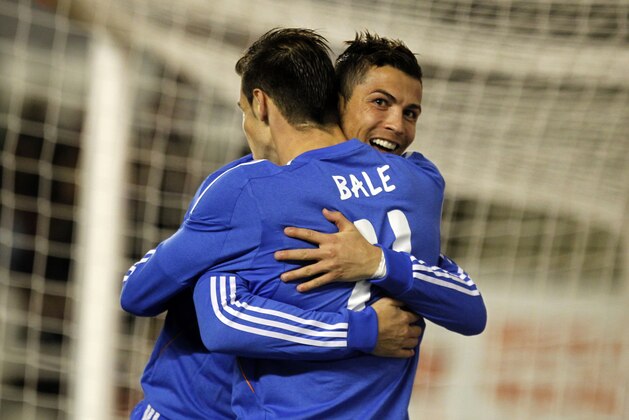 Real Madrid's Cristiano Ronaldo, background, from Portugal, celebrates with teammate Gareth Bale, from Wales, after scoring their side's third goal during Spanish La Liga soccer match between Real Madrid and Rayo Vallecano at the Vallecas stadium in Madrid, Saturday, Nov. 2, 2013. Ronaldo scored twice in Real Madrid's 3-2 victory. (AP Photo/Francisco Seco)