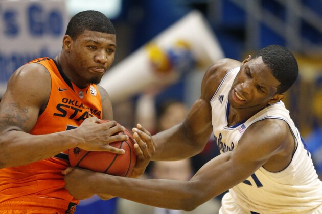Oklahoma State guard Marcus Smart (33) and Kansas center Joel Embiid (21) battle to a jump ball during the second half of an NCAA college basketball game at Allen Fieldhouse in Lawrence, Kan., Saturday, Jan. 18, 2014. Kansas defeated Oklahoma State 80-78. (AP Photo/Orlin Wagner)