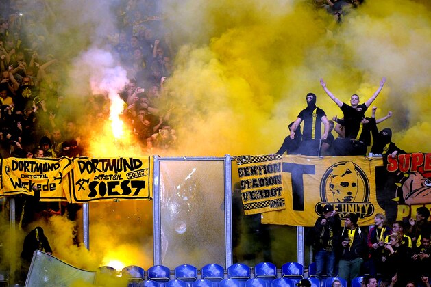 Dortmund fans throw fireworks on the pitch during the German soccer Bundesliga match between FC Schalke 04 and Borussia Dortmund in Gelsenkirchen, Germany, Saturday, Oct. 26, 2013. (AP Photo/Martin Meissner)