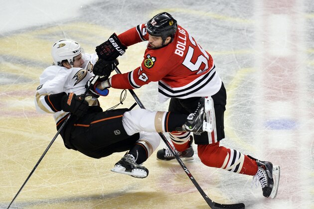 Chicago Blackhawks left wing Brandon Bollig, right, takes out Anaheim Ducks defenseman Ben Lovejoy during the third period of an NHL hockey game Friday, Dec. 6, 2013, in Chicago. The Ducks won 3-2 in a shootout. (AP Photo/Brian Kersey)
