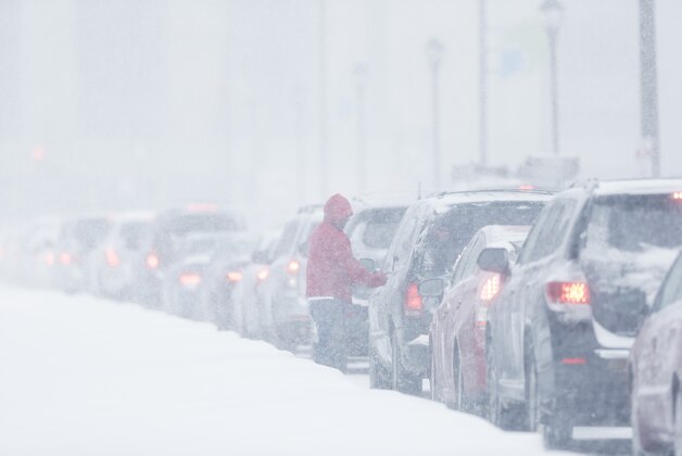 A man gets out of his car to clear the windows as traffic is at a standstill on John F Kennedy Boulevard during a winter snowstorm Tuesday, Jan. 21, 2014, in Philadelphia. A storm is sweeping across the Mid-Atlantic and New England. The National Weather Service said the storm could bring 8 to 12 inches of snow to Philadelphia and New York City, and more than a foot in Boston. (AP Photo/Matt Rourke)