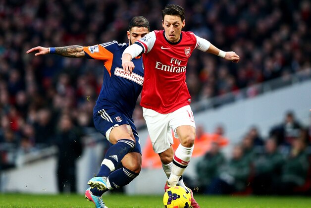 LONDON, ENGLAND - JANUARY 18:  Mesut Oezil of Arsenal takes on Ashkan Dejagah of Fulham during the Barclays Premier League match between Arsenal and Fulham at Emirates Stadium on January 18, 2014 in London, England.  (Photo by Clive Mason/Getty Images)
