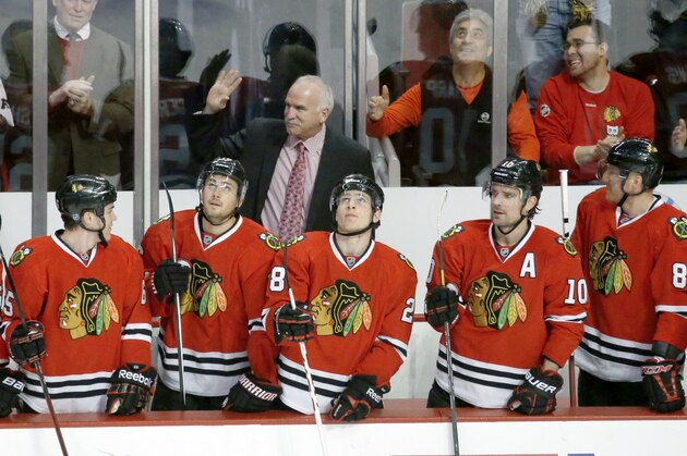 Chicago Blackhawks' Joel Quenneville waves to the crowd as the Blackhawks' acknowledge his recent 685th coaching win during the first period of an NHL hockey game against the Vancouver Canucks, Friday, Dec. 20, 2013, in Chicago. (AP Photo/Charles Rex Arbogast)