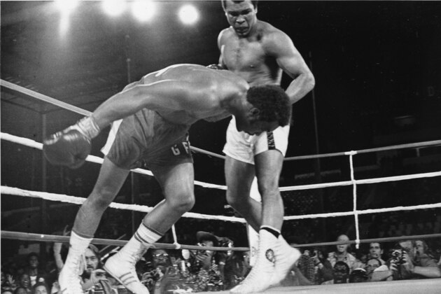 FILE - In this Oct. 30, 1974 file photo, Challenger Muhammad Ali watches as defending world champion George Foreman goes down to the canvas in the eighth round of their WBA/WBC championship match in Kinshasa, Zaire, on Oct. 30, 1974. Foreman was counted out by the referee and Ali regained the world heavyweight crown by knockout in the bout dubbed