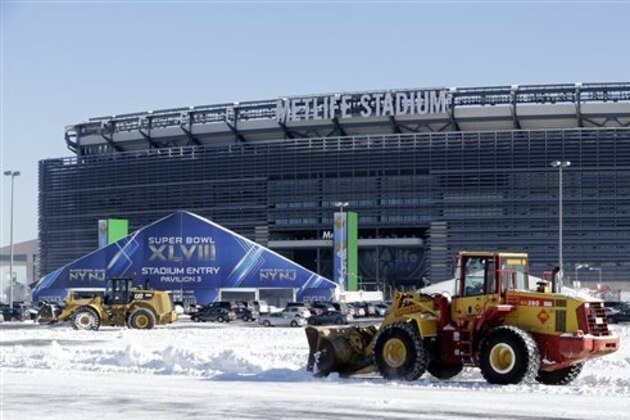Tractors plow snow off the parking lot of MetLife Stadium near a tent which will serve as an access point into Super Bowl XLVIII as crews removed snow following a snow storm, Wednesday, Jan. 22, 2014, in East Rutherford, N.J.  Super Bowl XLVIII, which will be played between the Denver Broncos and the Seattle Seahawks on Feb. 2, will be the first NFL title game held outdoors in a city where it snows. (AP Photo/Julio Cortez)
