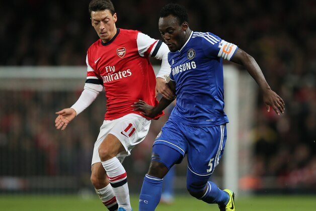 Chelsea's Michael Essien, centre, shields the ball from Arsenal's Mesut Ozil during their English League Cup soccer match between Arsenal and Chelsea at the Emirates stadium in London Tuesday, Oct. 29, 2013. (AP Photo/Alastair Grant)