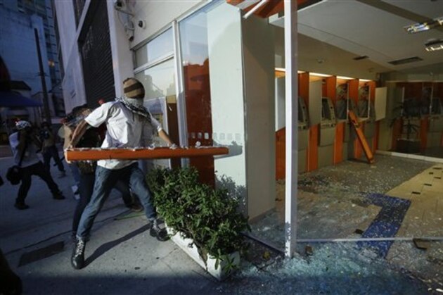 Demonstrators destroy a bank to protest the upcoming World Cup soccer tournament and demand better public services in Sao Paulo, Brazil, Saturday, Jan. 25, 2014. Last year, millions of people took to the streets across Brazil complaining of higher bus fares, poor public services and corruption while the country spends billions on the World Cup, which is scheduled to start in June. (AP Photo/Nelson Antoine)
