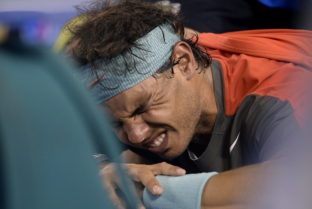 Rafael Nadal of Spain grimaces as he receives a medical treatment to his back in the men's singles final against Stanislas Wawrinka of Switzerland at the Australian Open tennis championship in Melbourne, Australia, Sunday, Jan. 26, 2014.(AP Photo/Andrew Brownbill)
