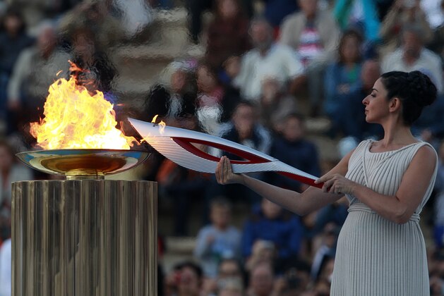 Actress Ino Menegaki, playing the role of  high priestess, lights the torch with the Olympic Flame during a handover ceremony in Athens' Panathinaiko Stadium, on Saturday, Oct. 5, 2013. The Olympic flame has been handed to organizers of the Sochi Winter Olympics in a ceremony at the site of the first modern summer games. After a seven-day run through Greece, the flame will cover 40,000 miles on Russian soil. The record-setting relay will start on Monday in Moscow and finish in Sochi on Feb. 7, the opening day of the games. (AP Photo/Kostas Tsironis)