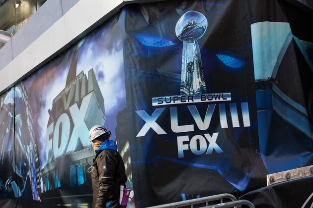 NEW YORK, NY - JANUARY 24:  A construction worker walks past an advertisement for Super Bowl XLVIII, which will be played in East Rutherford, NJ in two weekends, on January 24, 2014 in Times Square in New York City.  In preperation for the Super Bowl, New York City is turning sections of Times Square and Broadway into 'Super Bowl Boulevard,' which will feature events such as games, concerts and a toboggan run.  (Photo by Andrew Burton/Getty Images)