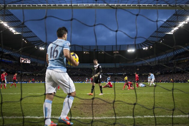 Manchester City's Sergio Aguero, centre left, gathers the ball from the net after a goal by teammate Yaya Toure, bottom third right, during their 4-2 win against Cardiff City in their English Premier League soccer match at the Etihad Stadium, Manchester, England, Saturday Jan 18, 2014. (AP Photo/Jon Super)