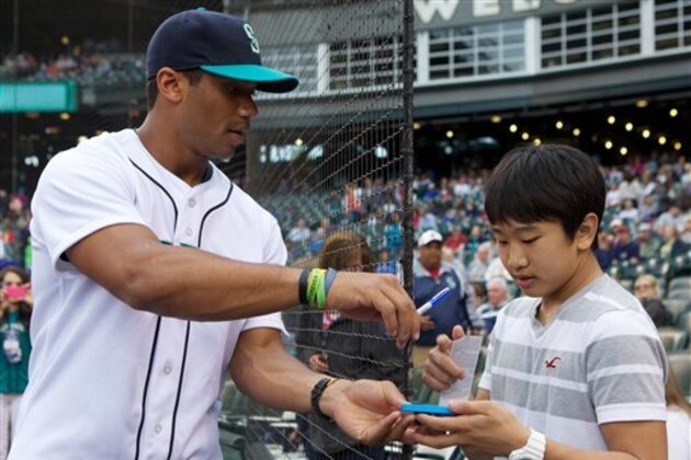 Seattle Seahawks quarterback Russell Wilson signs an autograph for a young fan before a game between the Seattle Mariners and the New York Yankees, Friday, June 7, 2013, in Seattle. Wilson was on hand to throw out the first pitch (AP Photo/Stephen Brashear) Seattle Seahawks quarterback Russell Wilson signs an autograph for a young fan before a game between the Seattle Mariners and the New York Yankees, Friday, June 7, 2013, in Seattle. Wilson was on hand to throw out the first pitch (AP Photo/Stephen Brashear)