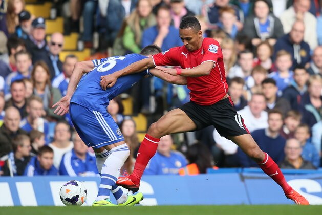 Chelsea's John Terry, left, is tackled by Cardiff's Peter Odemwingie during their English Premier League soccer match at Chelsea's Stamford Bridge stadium in London, Saturday Oct. 19, 2013. (AP Photo/Alastair Grant)