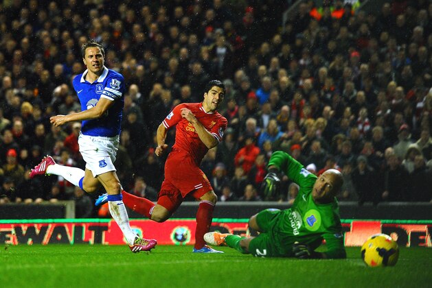 LIVERPOOL, ENGLAND - JANUARY 28:  Luis Suarez of Liverpool scores his team's fourth goal past goalkeeper Tim Howard of Everton as Phil Jagielka of Everton closes in during the Barclays Premier League match between Liverpool and Everton at Anfield on January 28, 2014 in Liverpool, England.  (Photo by Laurence Griffiths/Getty Images)