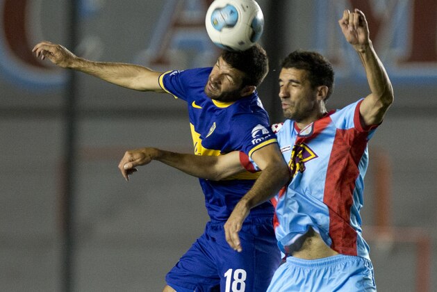 Boca Juniors' Emmanuel Gigliotti, left, goes for a header with Arsenal's Mariano Echeverria during an Argentine league soccer match in Buenos Aires, Argentina, Sunday, Nov. 17, 2013. (AP Photo/Eduardo Di Baia)