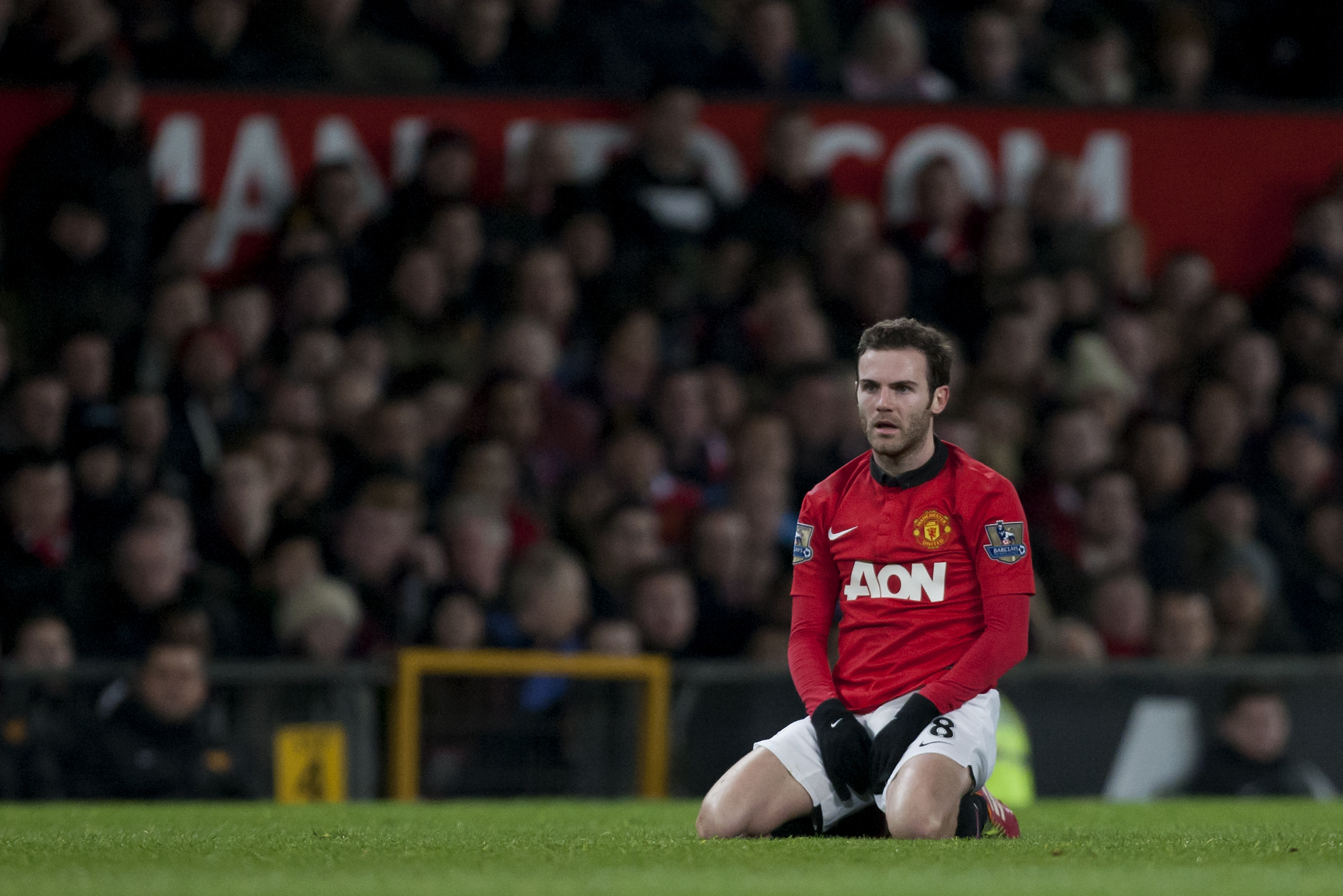 Manchester United's Juan Mata kneels on the pitch during his team's 2-0 win against Cardiff City in their English Premier League soccer match at Old Trafford Stadium, Manchester, England, Tuesday Jan. 28, 2014. (AP Photo/Jon Super)