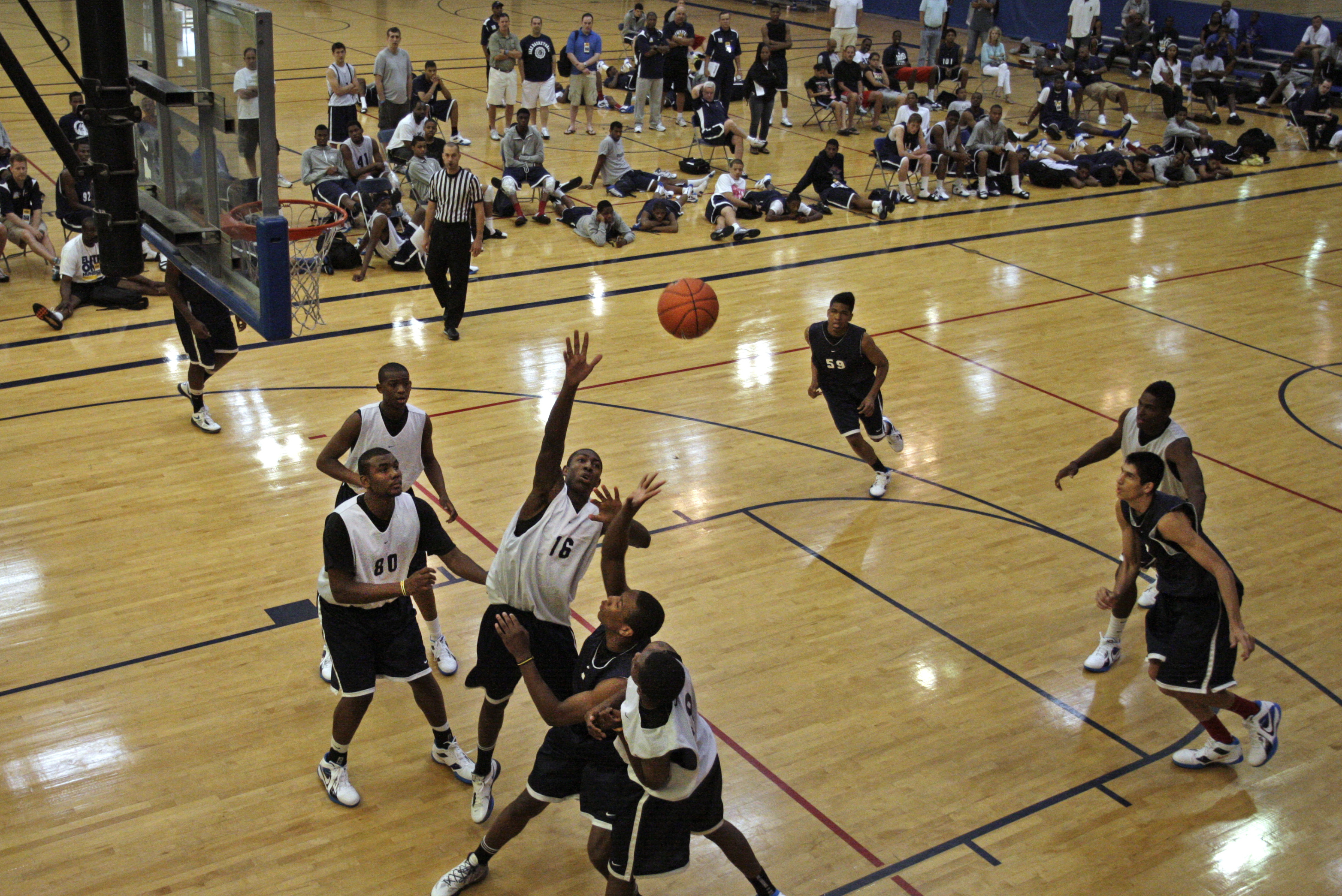 In this June 12, 2011, photo, Nike Elite 100  basketball camp attendees watch their fellow campers play in the championship game in St. Louis. Even as it polices the summer circuit, the NCAA is working to rewrite its men's basketball recruiting rules in an effort to reduce the potentially unsavory influences of AAU coaches and event operators. (AP Photo/Tom Gannam)