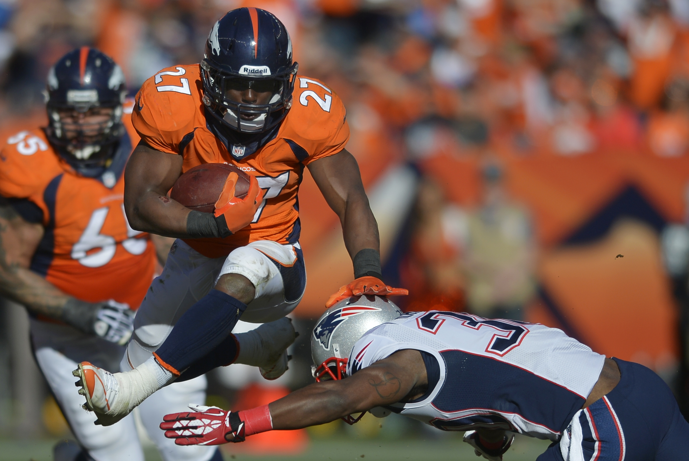 Denver Broncos running back Knowshon Moreno (27) leaps over New England Patriots strong safety Duron Harmon (30) during the first half of the AFC Championship NFL playoff football game in Denver, Sunday, Jan. 19, 2014. (AP Photo/Jack Dempsey)
