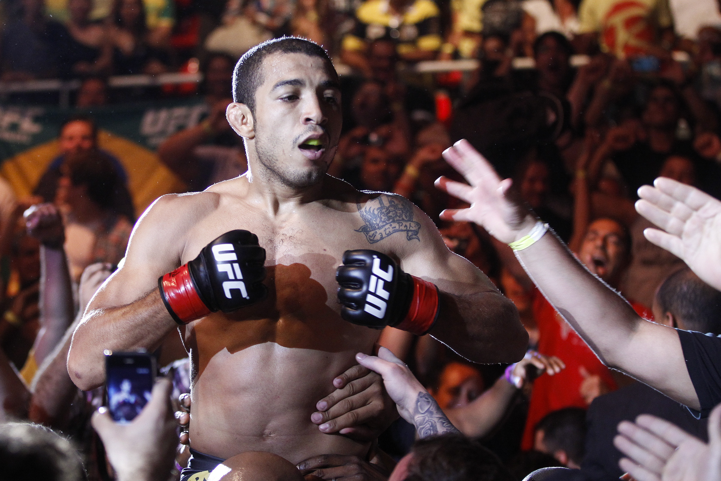 Defending featherweight champion Jose Aldo, from Brazil, celebrates with fans after defeating Chad Mendes, from the US, on the first round during their featherweight title bout at the Ultimate Fighting Championship (UFC) 142 in Rio de Janeiro, Brazil, Sunday Jan. 15, 2012. (AP Photo/Felipe Dana)