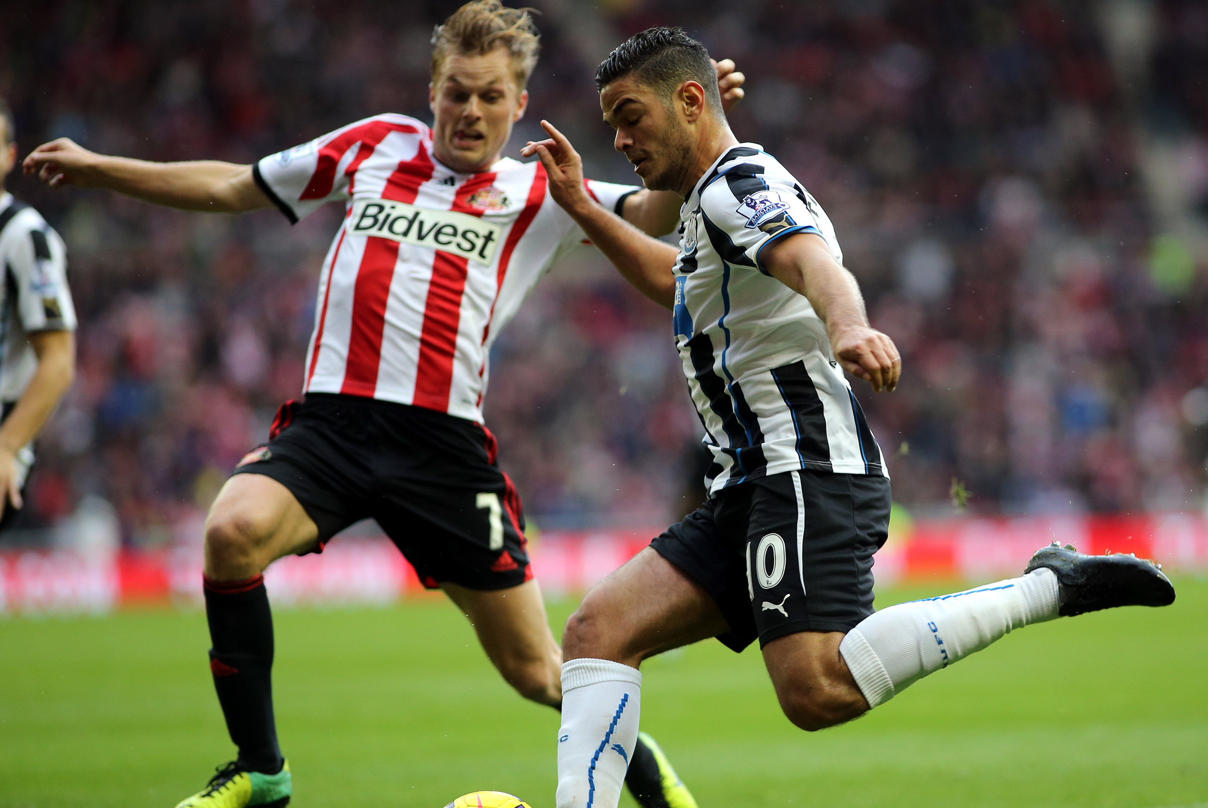 Newcastle United's Hatem Ben Arfa, right, has a shot towards goal past Sunderland's Seb Larsson, left, during their English Premier League soccer match at the Stadium of Light, Sunderland, England, Sunday, Oct. 27, 2013. (AP Photo/Scott Heppell)