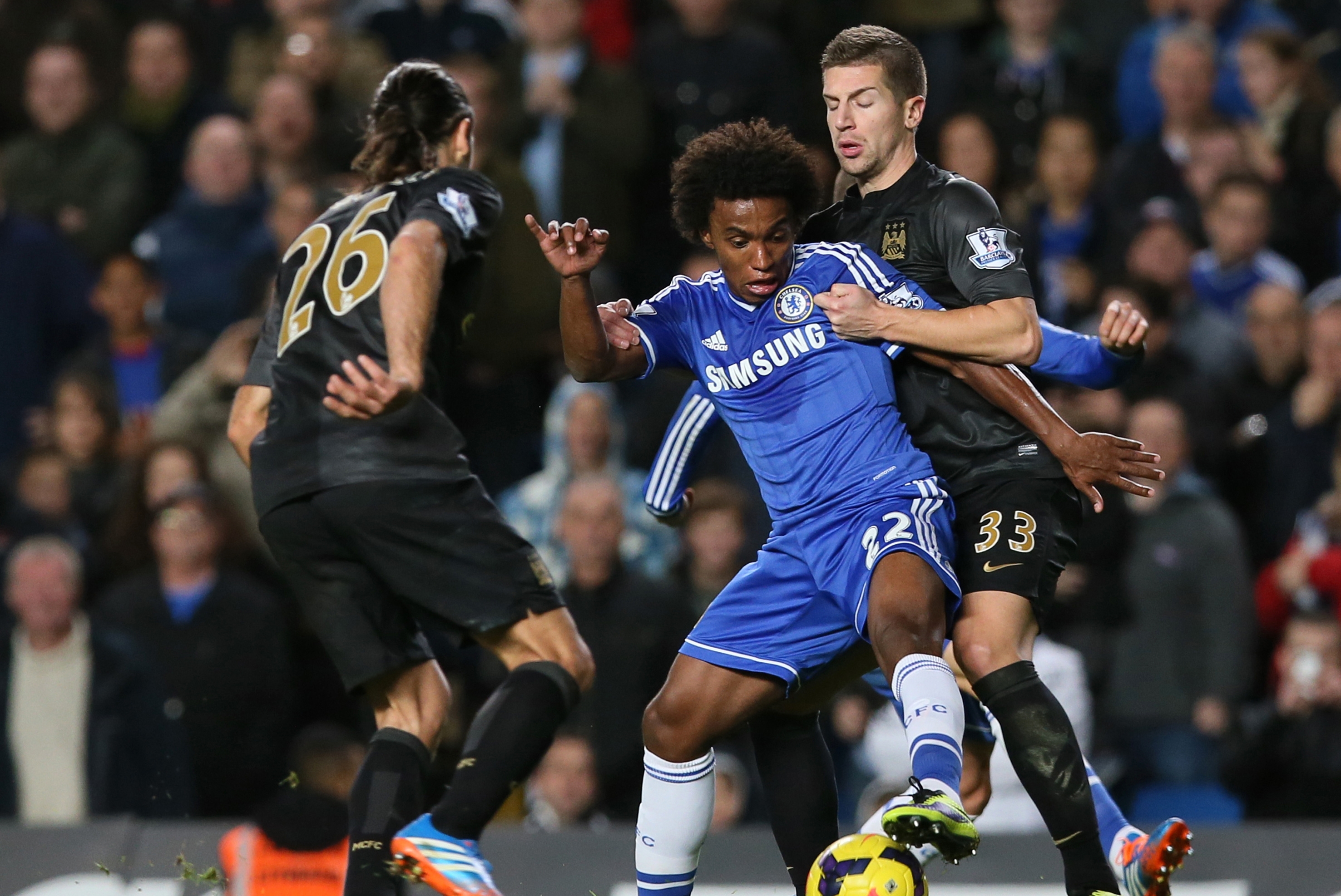 Chelsea's Willian, centre, is tackled by Manchester City's Matija Nastasic, right, during their English Premier League soccer match between Chelsea and Manchester City at Stamford Bridge stadium in London, Sunday, Oct.  27, 2013. (AP Photo/Alastair Grant)