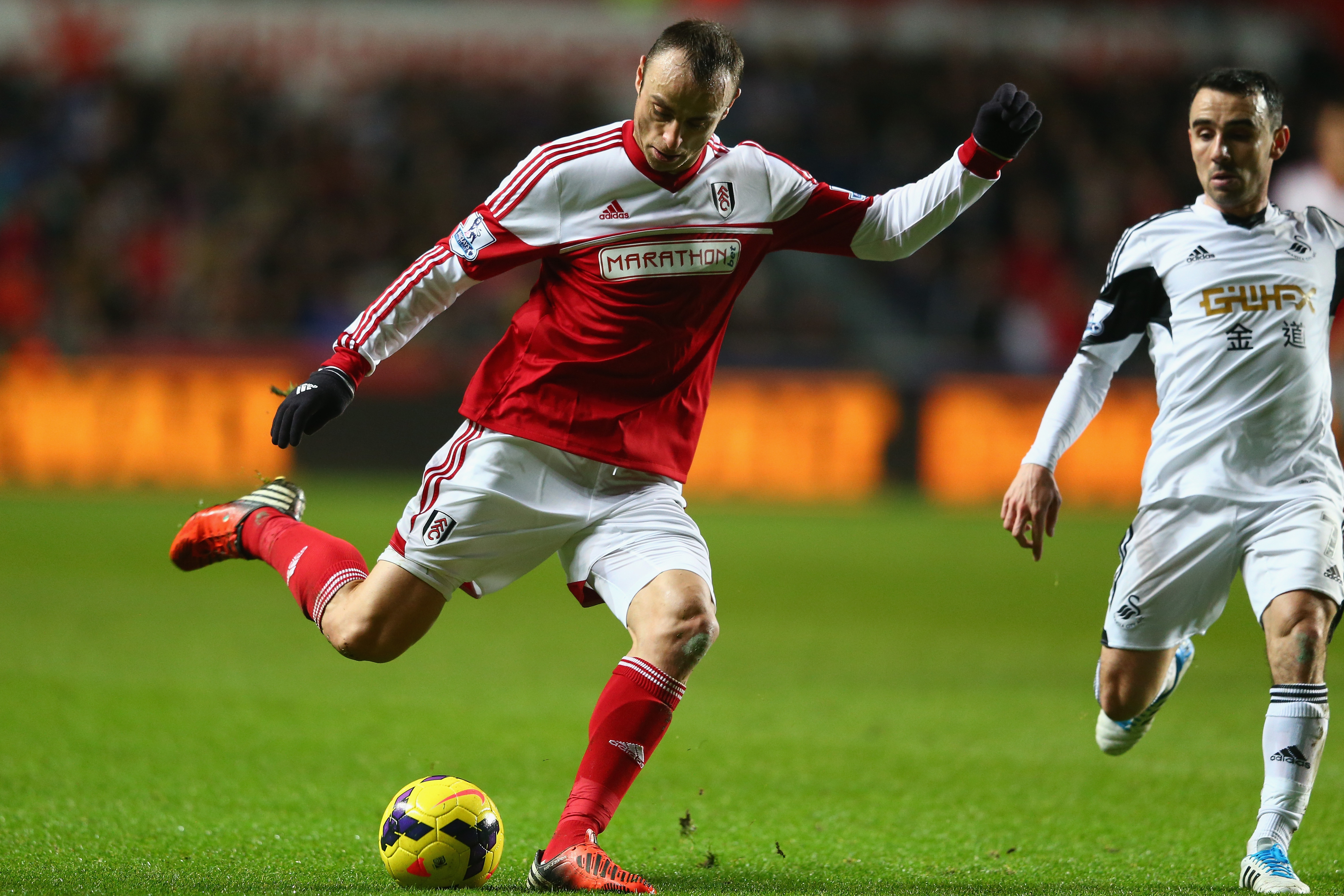 SWANSEA, WALES - JANUARY 28:  Dimitar Berbatov (L) of Fulham shoots asLeon Britton  (R) of Swansea City closes in during the Barclays Premier League match between Swansea City and Fulham at the Liberty Stadium on January 28, 2014 in Swansea, Wales.  (Photo by Michael Steele/Getty Images)