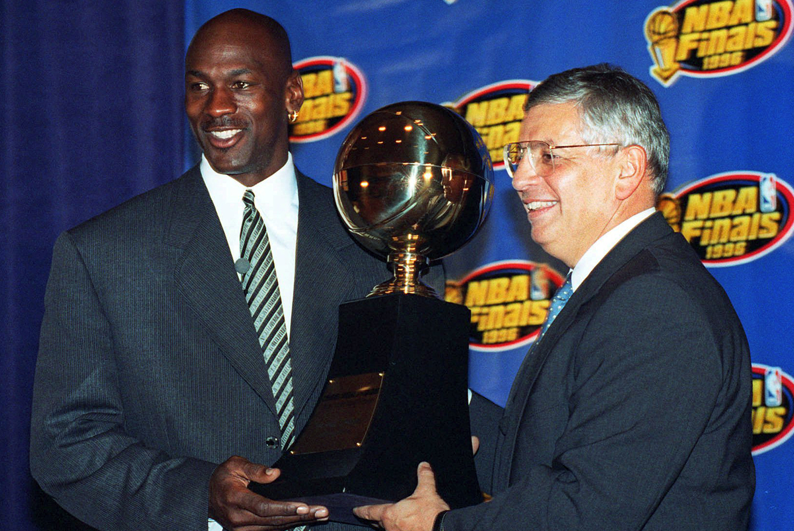 FILE - In this June 18, 1996, file photo, Chicago Bulls' Michael Jordan, left, receives the NBA Finals Most Valuable Player trophy from Commissioner David Stern during a ceremony in Chicago. Stern is not in the Hall of Fame, he never played in an All-Star game and he is about a foot shorter than most NBA stars. But try to find an NBA legacy more lasting than Stern's, who is retiring Saturday, Feb. 1, after exactly 30 years on the job. (AP Photo/Charles Bennett, File)