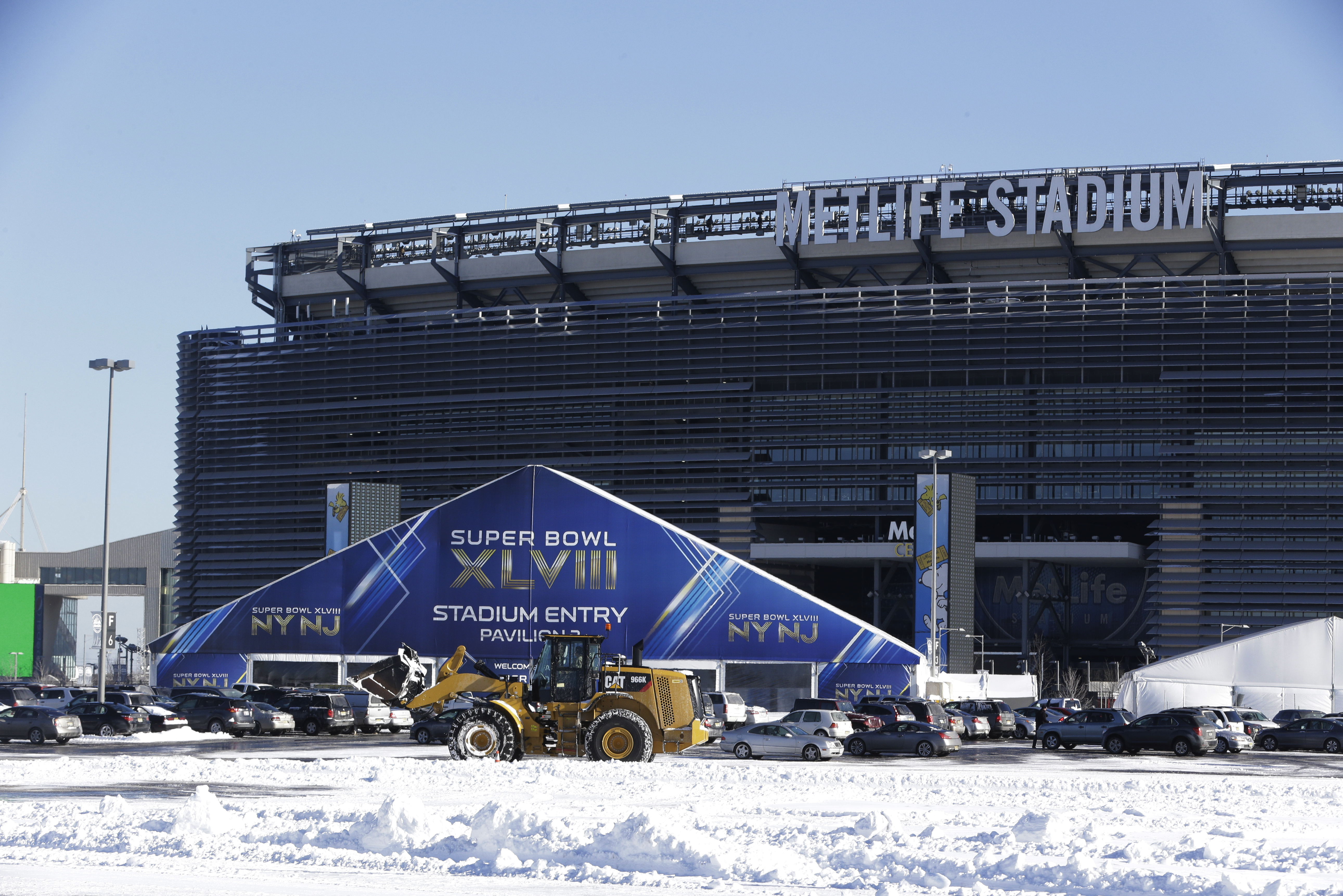 A tractor plows snow off the parking lot of MetLife Stadium near a tent which will serve as an access point into Super Bowl XLVIII as crews removed snow following a snow storm, Wednesday, Jan. 22, 2014, in East Rutherford, N.J.  Super Bowl XLVIII, which will be played between the Denver Broncos and the Seattle Seahawks on Feb. 2, will be the first NFL title game held outdoors in a city where it snows. (AP Photo/Julio Cortez)