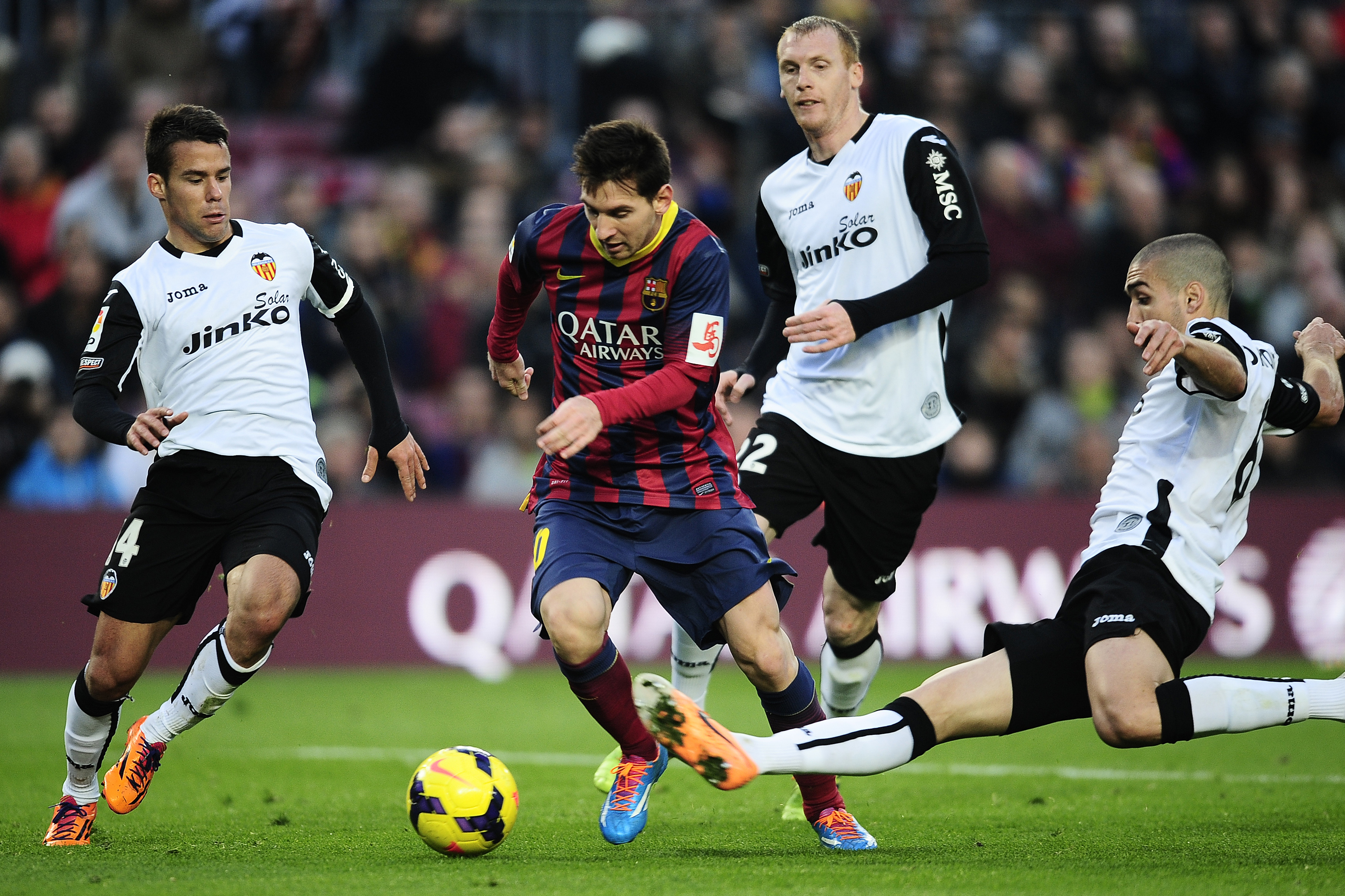 FC Barcelona's Lionel Messi, second left, duels the ball against Valencia's Juan Bernat, left, and Oriol Romeu, right, during a Spanish La Liga soccer match at the Camp Nou stadium in Barcelona, Spain, Saturday, Feb. 1, 2014. (AP Photo/Manu Fernandez)