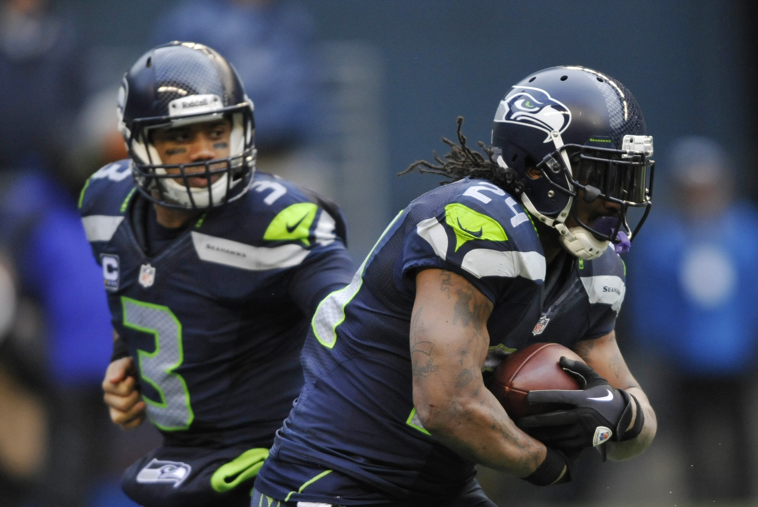 Jan 11, 2014; Seattle, WA, USA; Seattle Seahawks running back Marshawn Lynch (24) receives the hand off from quarterback Russell Wilson (3) against the New Orleans Saints during the second half of the 2013 NFC divisional playoff football game at CenturyLink Field. Mandatory Credit: Steven Bisig-USA TODAY Sports