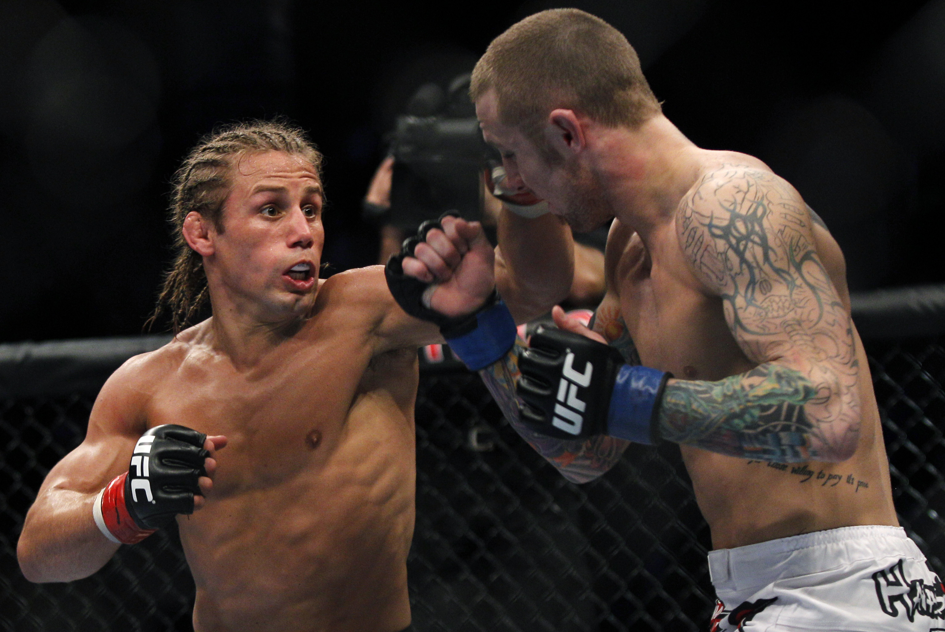 Urijah Faber, left, hits Eddie Wineland during their mixed martial arts match at UFC 128  Saturday, March 19, 2011, in Newark, N.J. Faber won by unanimous decision. (AP Photo/Mel Evans)