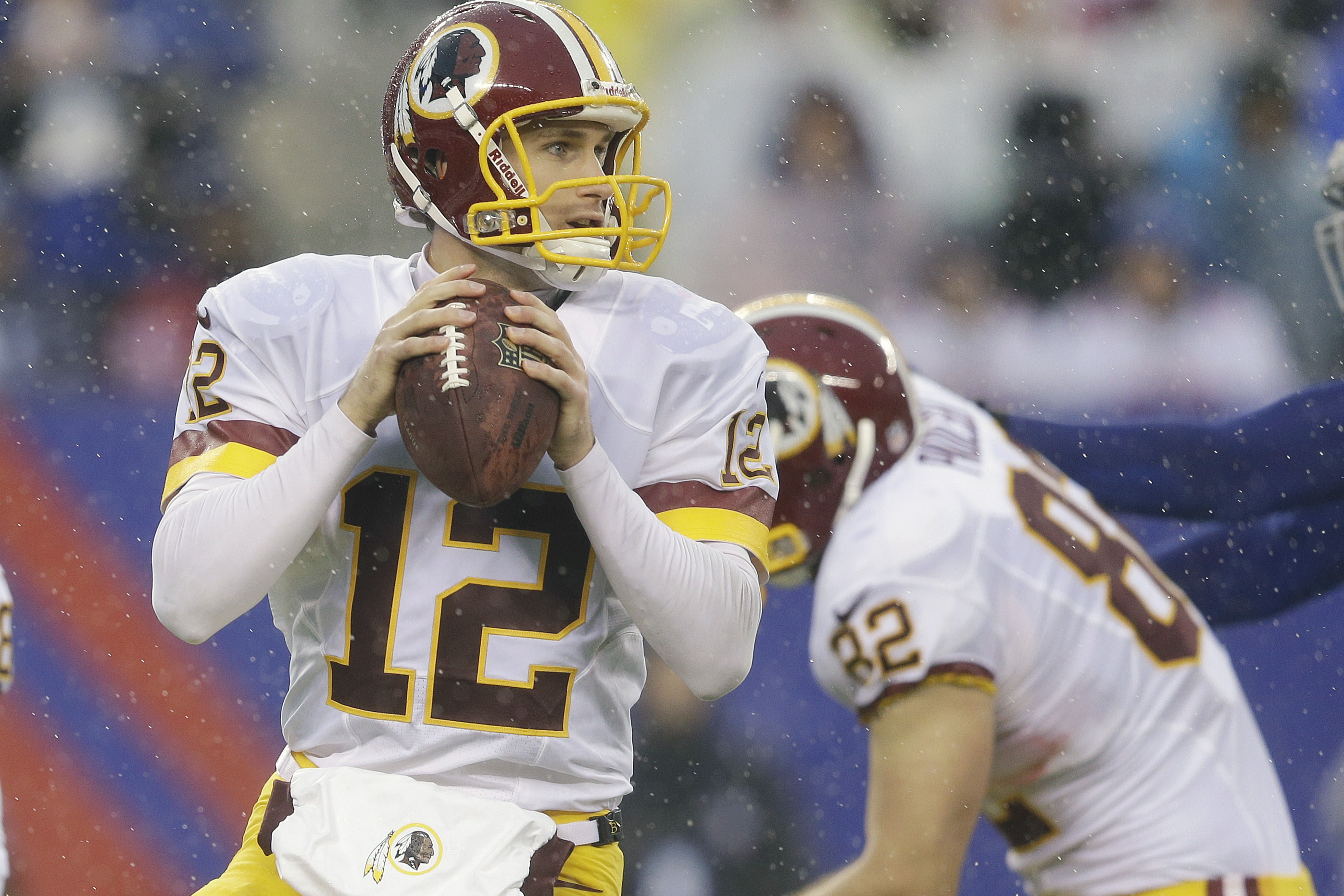 In the rain, Washington Redskins quarterback Kirk Cousins (12) looks to pass during the first half of an NFL football game against the New York Giants, Sunday, Dec. 29, 2013, in East Rutherford, N.J.  (AP Photo/Julio Cortez)