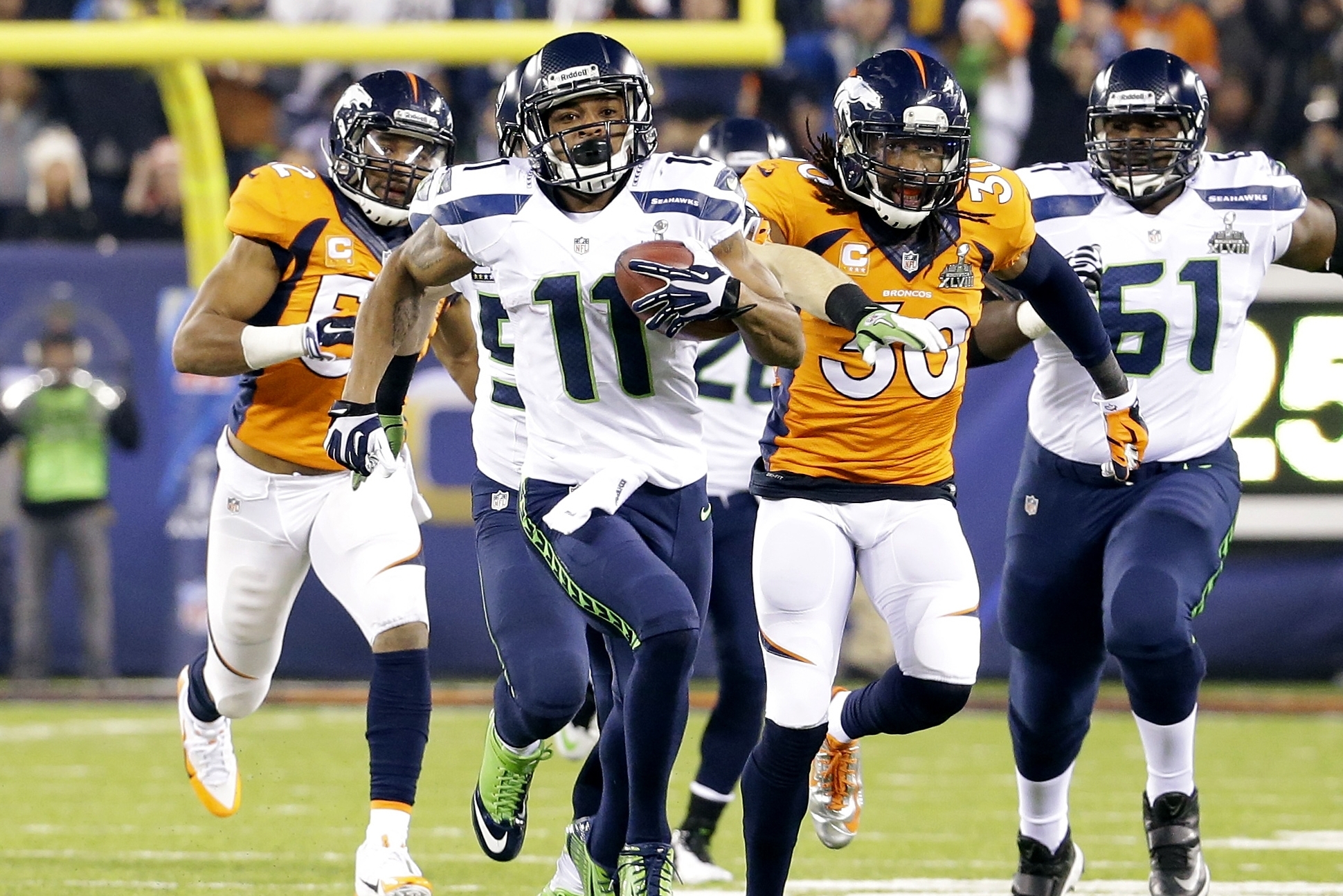 Seattle Seahawks' Percy Harvin (11) runs from Denver Broncos' David Bruton (30) while returning a kickoff 87-yards for a touchdown during the second half of the NFL Super Bowl XLVIII football game Sunday, Feb. 2, 2014, in East Rutherford, N.J.  (AP Photo/Ted S. Warren)