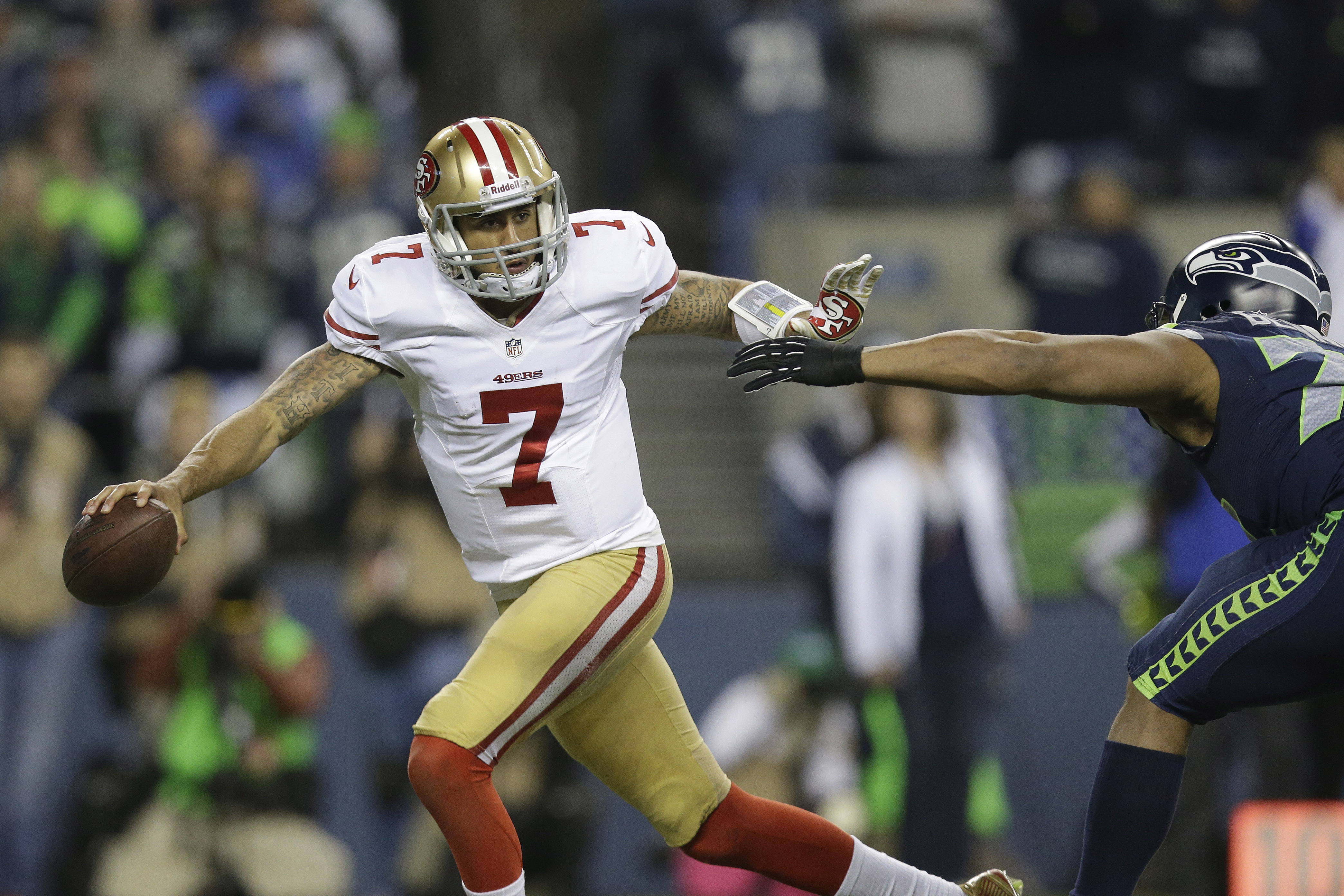 San Francisco 49ers' Colin Kaepernick (7) moves away from Seattle Seahawks' Michael Bennett (72) during the second half of the NFL football NFC Championship game Sunday, Jan. 19, 2014, in Seattle. (AP Photo/Marcio Jose Sanchez)