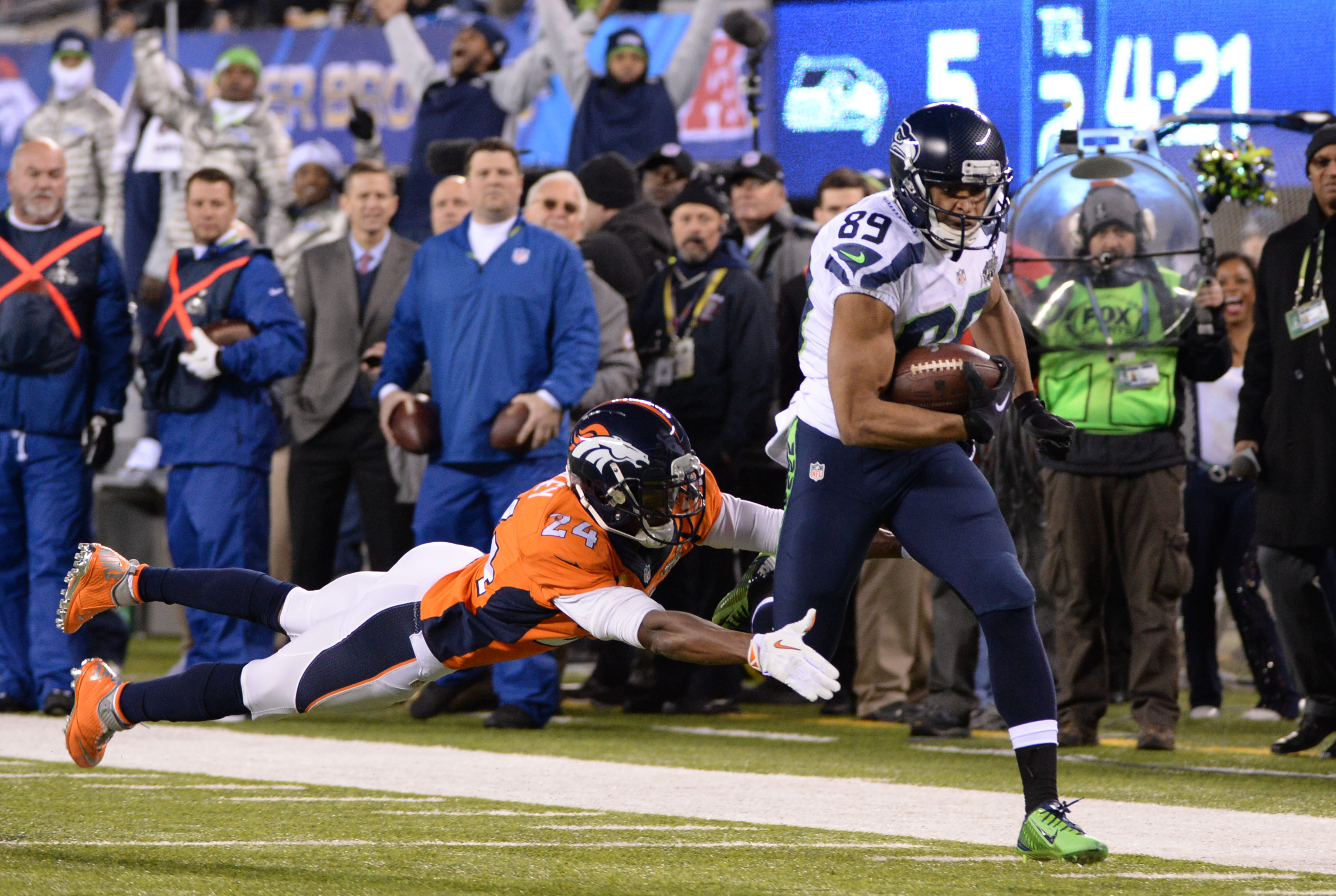 Feb 2, 2014; East Rutherford, NJ, USA; Denver Broncos cornerback Champ Bailey (24) dives to tackle a sprinting Seattle Seahawks wide receiver Doug Baldwin (89) in Super Bowl XLVIII at MetLife Stadium.  Mandatory Credit: Robert Deutsch-USA TODAY Sports