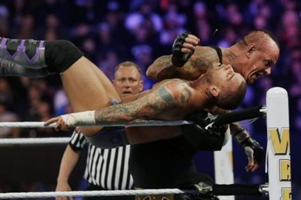 Wrestler Mark William Calaway, known as Undertaker, right, hits Phillip Jack Brooks known as CM Punk  as they wrestle Sunday, April 7, 2013, in East Rutherford, N.J., during Wrestlemania. (AP Photo/Mel Evans)