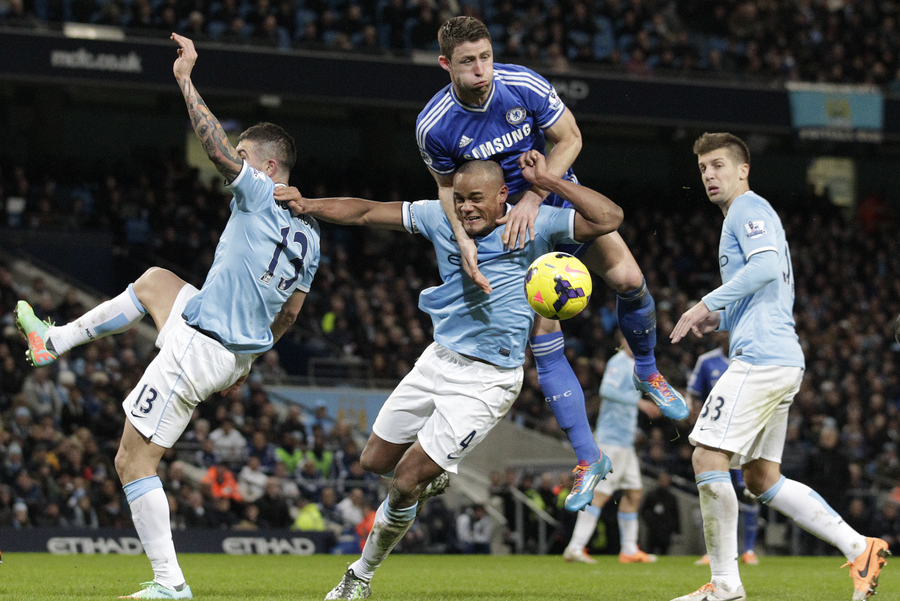 Manchester City's Vincent Kompany, centre bottom is out jumped for the ball by Chelsea's Gary Cahill during their English Premier League soccer match at the Etihad Stadium, Manchester, England, Monday Feb. 3, 2014. (AP Photo/Jon Super)