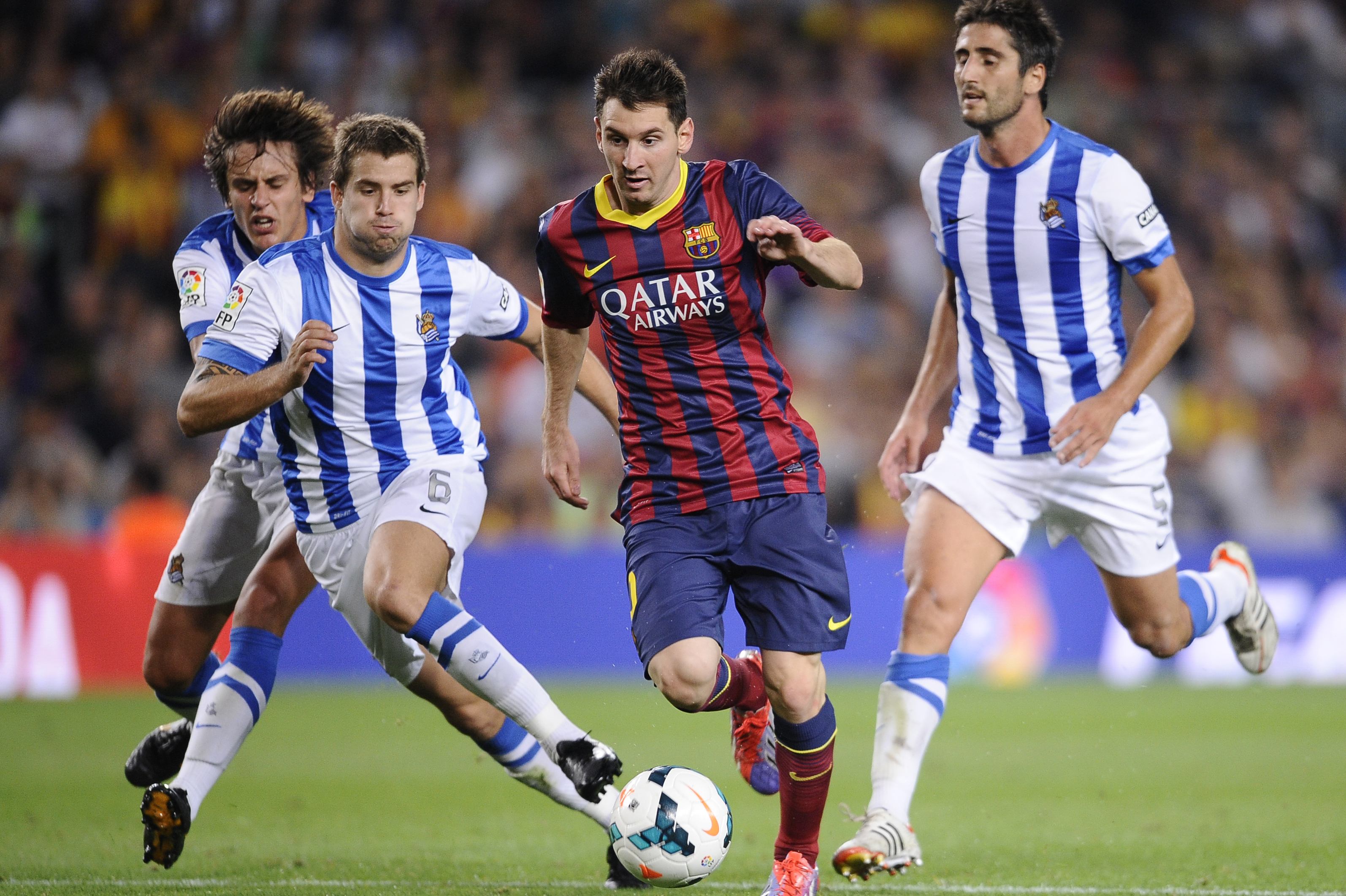 FC Barcelona's Lionel Messi, from Argentina, second right, duels for the ball against Real Sociedad's Inigo Martinez, second left, during a Spanish La Liga soccer match at the Camp Nou stadium in Barcelona, Spain, Tuesday, Sept. 24, 2013. (AP Photo/Manu Fernandez)