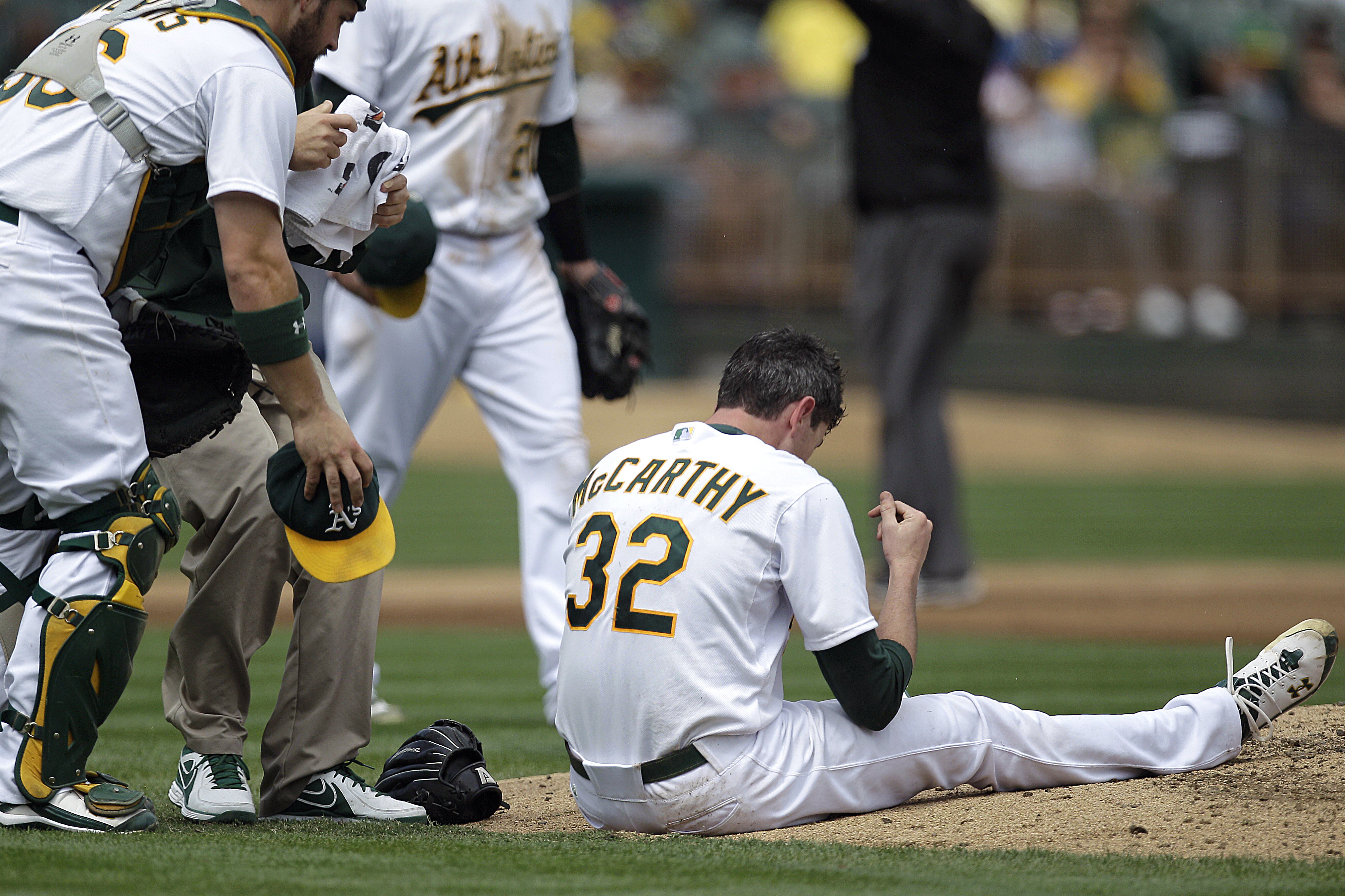 FILE - In this Sept. 5, 2012, file hoto, Oakland Athletics catcher Derek Norris, left, comes to the aid of pitcher Brandon McCarthy (32) who was hit in the head by a ball hit by Los Angeles Angels' Erick Aybar in the fourth inning of a baseball game in Oakland, Calif. Major League Baseball has approved a protective cap for pitchers, hoping to reduce the effects of being hit in the head by line drives. (AP Photo/Ben Margot, File)