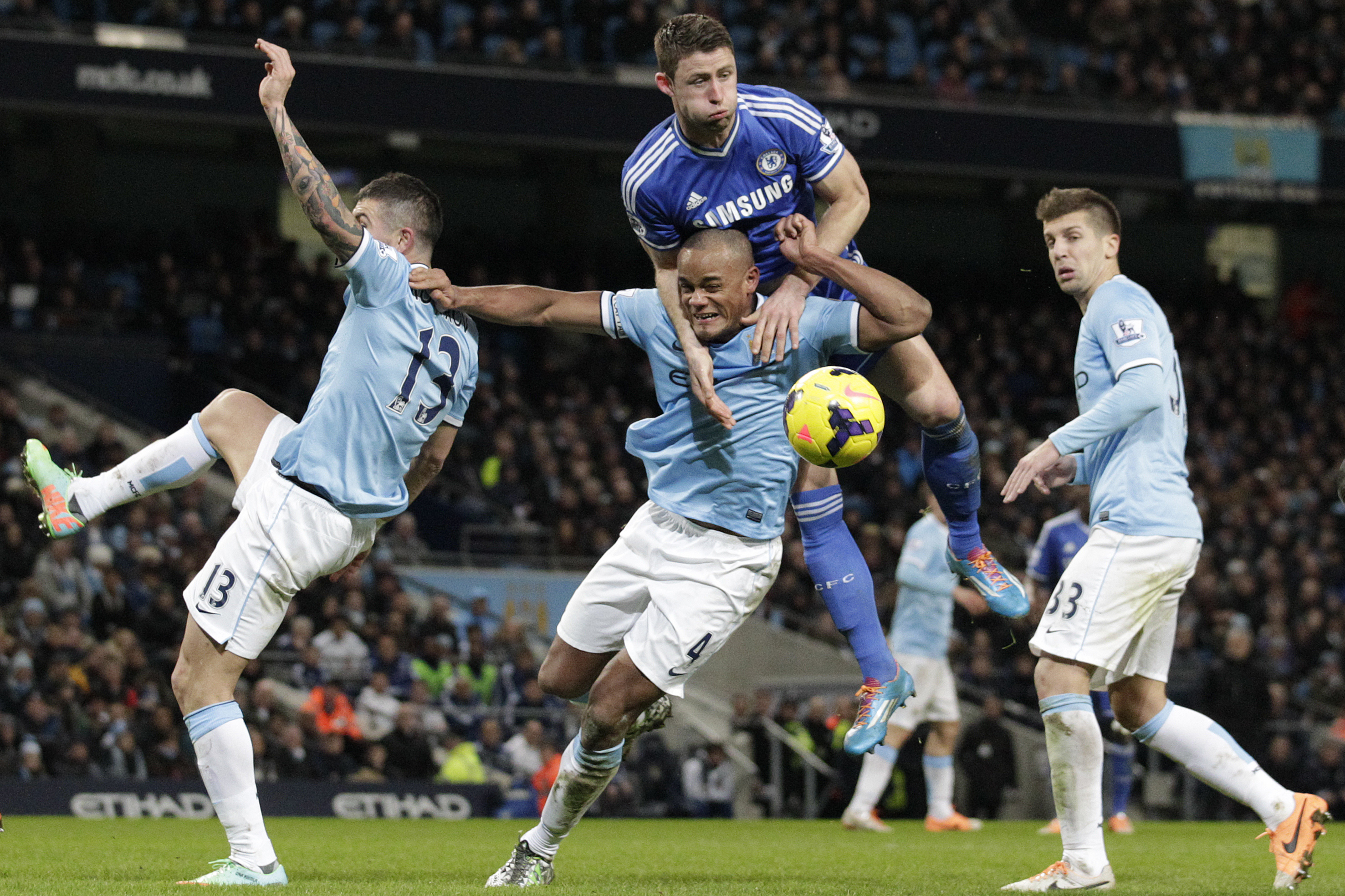 Manchester City's Vincent Kompany, centre bottom is out jumped for the ball by Chelsea's Gary Cahill during their English Premier League soccer match at the Etihad Stadium, Manchester, England, Monday Feb. 3, 2014. (AP Photo/Jon Super)