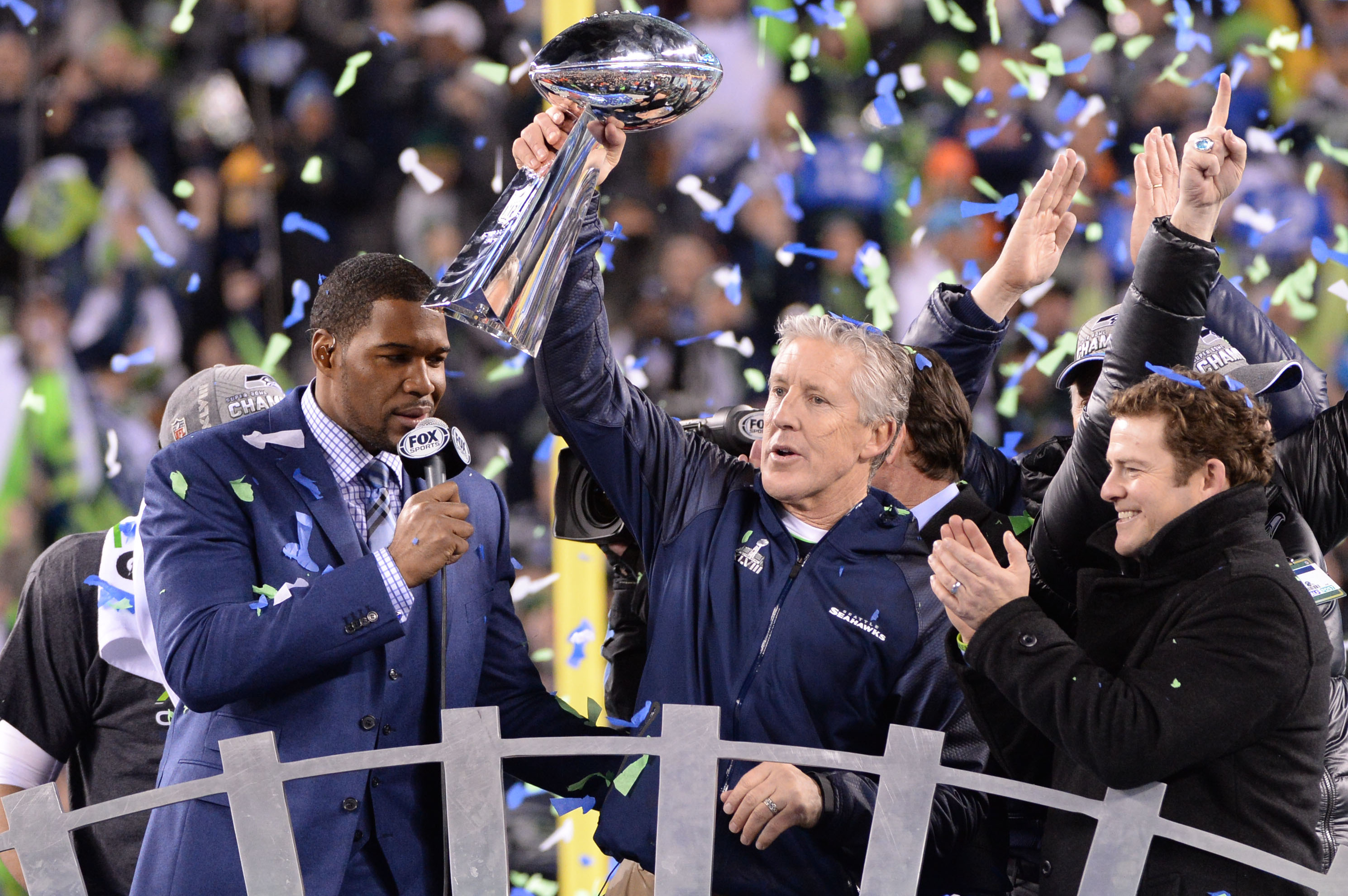 Feb 2, 2014; East Rutherford, NJ, USA; Seattle Seahawks head coach Pete Carroll raises the Lombardi Trophy after winning  Super Bowl XLVIII at MetLife Stadium.  At left is Fox Sports's Michael Strahan and at right is Seahawks General Manager John Schneider. Mandatory Credit: Robert Deutsch-USA TODAY Sports