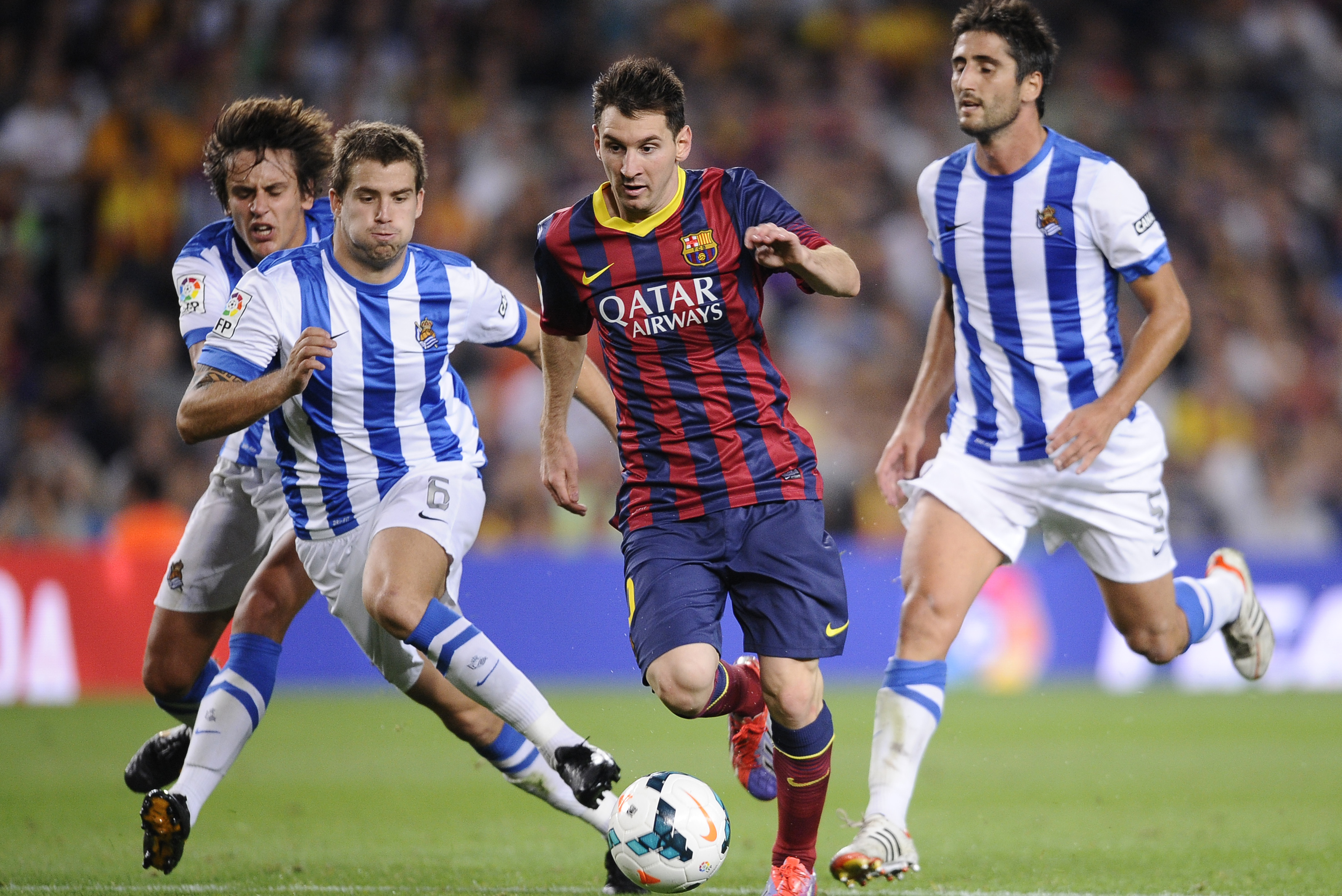 FC Barcelona's Lionel Messi, from Argentina, second right, duels for the ball against Real Sociedad's Inigo Martinez, second left, during a Spanish La Liga soccer match at the Camp Nou stadium in Barcelona, Spain, Tuesday, Sept. 24, 2013. (AP Photo/Manu Fernandez)