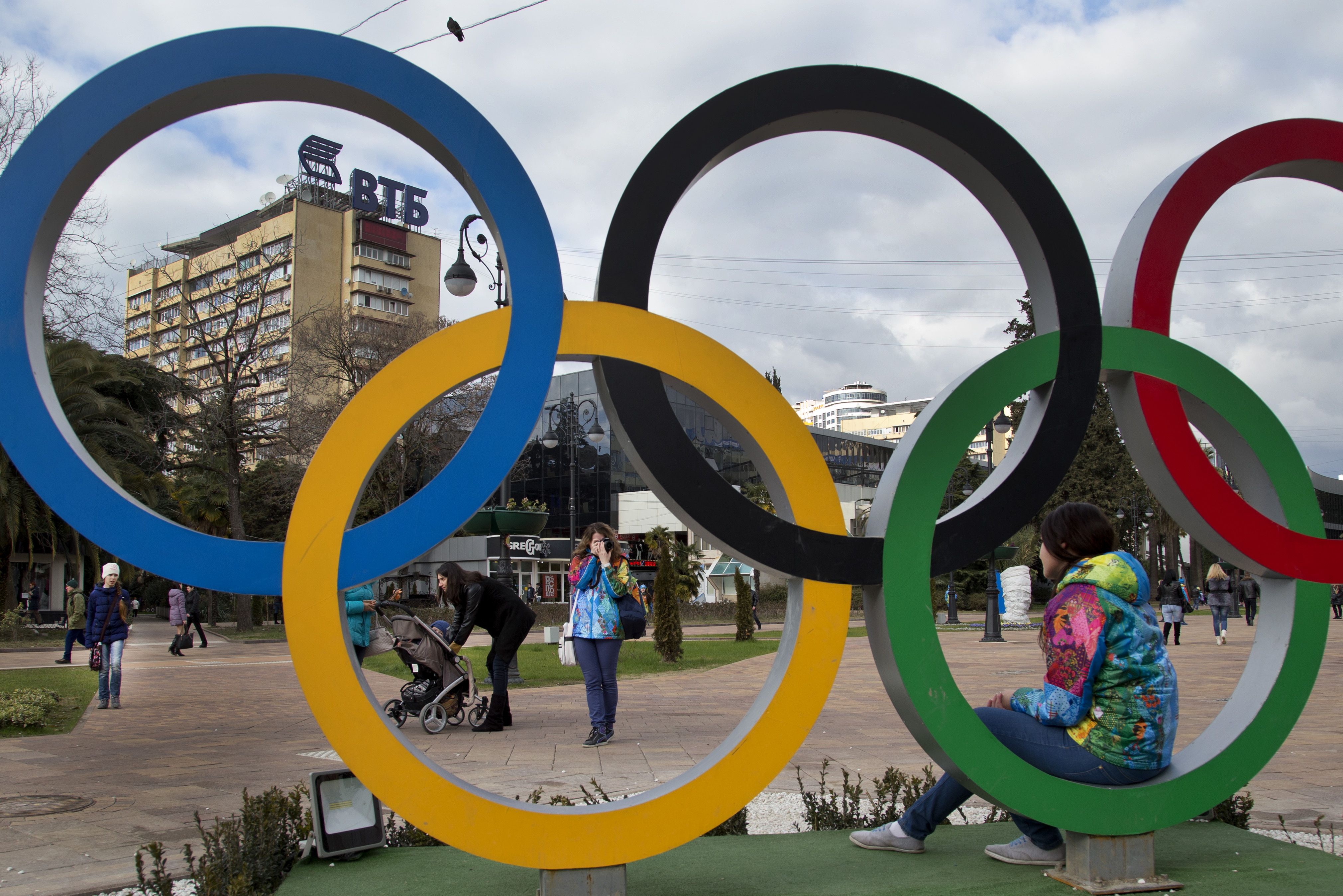 A Russian Olympic volunteer poses for snapshots next to the Olympic rings in Sochi, Russia, Tuesday, Feb. 4, 2014. The opening ceremony for the  2014 Winter Olympics will be held on Feb. 7. (AP Photo/Bernat Armangue)