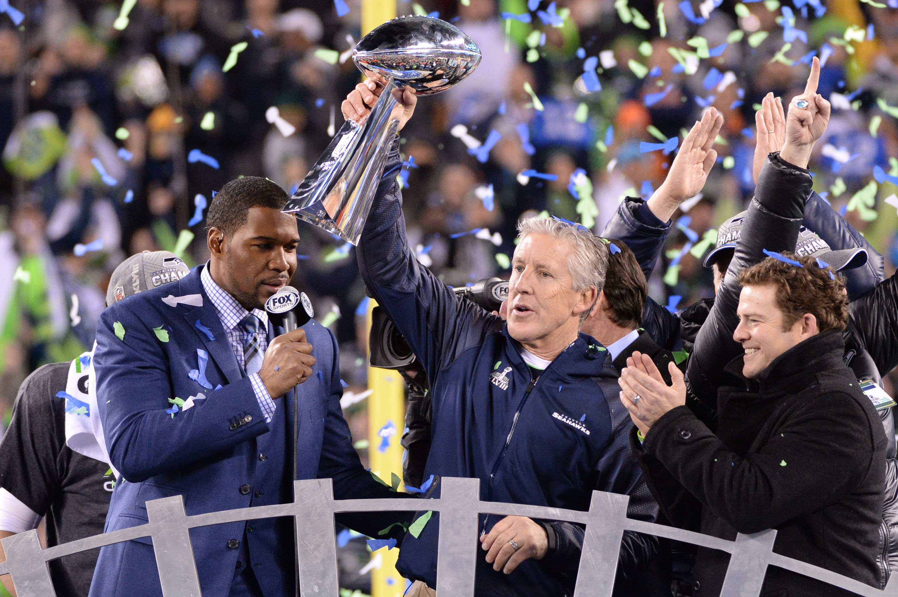 Feb 2, 2014; East Rutherford, NJ, USA; Seattle Seahawks head coach Pete Carroll raises the Lombardi Trophy after winning  Super Bowl XLVIII at MetLife Stadium.  At left is Fox Sports's Michael Strahan and at right is Seahawks General Manager John Schneider. Mandatory Credit: Robert Deutsch-USA TODAY Sports