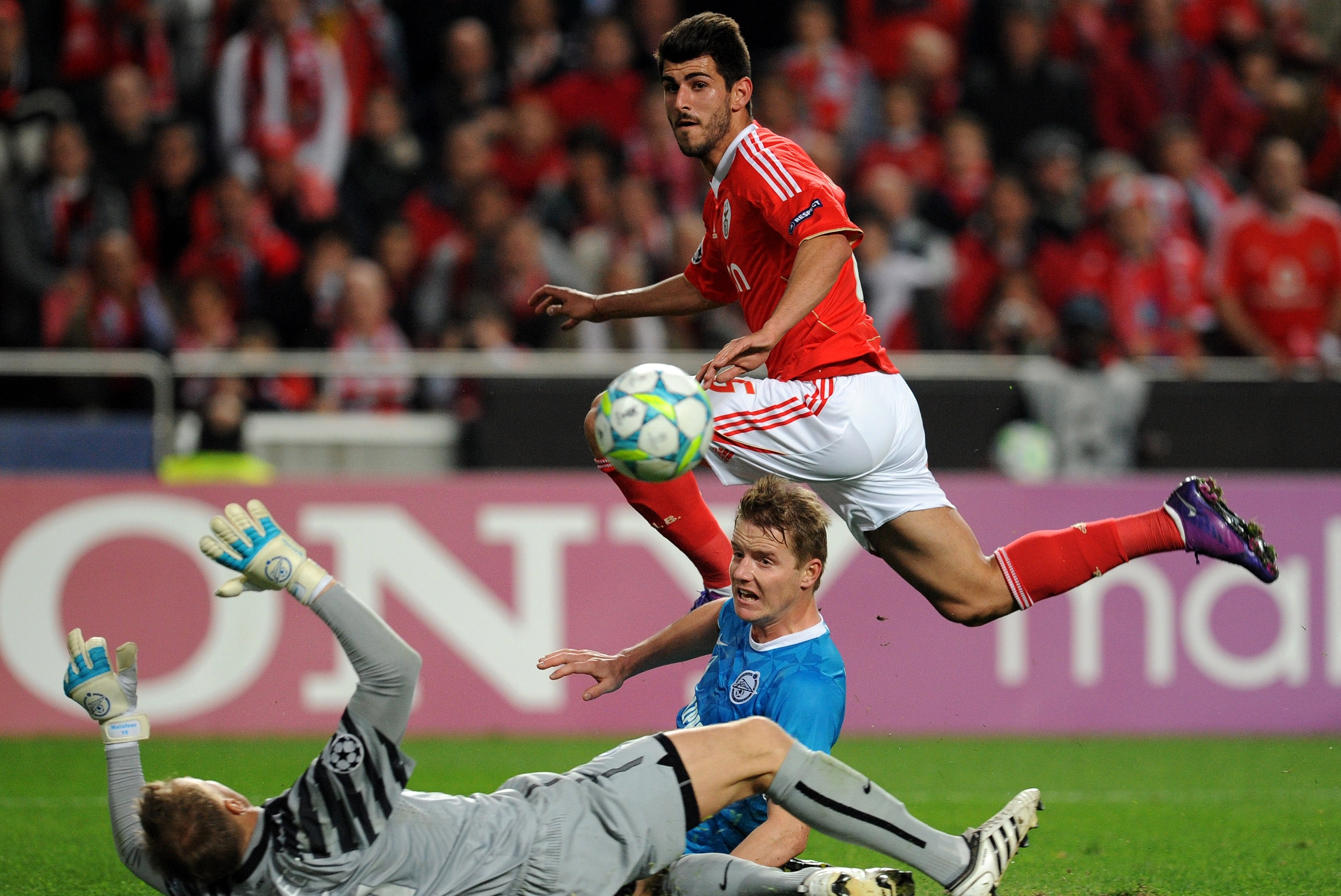 Benfica's Nelson Oliveira, right on top, scores past FC Zenit St Petersburg's Tomas Hubocan, from Slovakia, and goalkeeper Vyacheslav Malafeev during their Champions League round of 16 2nd leg soccer match at Benfica's Luz Stadium, in Lisbon, Tuesday Feb. 6, 2012. Benfica won the match 2-0 (4-3 on aggregate) and qualified for the next round.(AP Photo/Paulo Duarte)