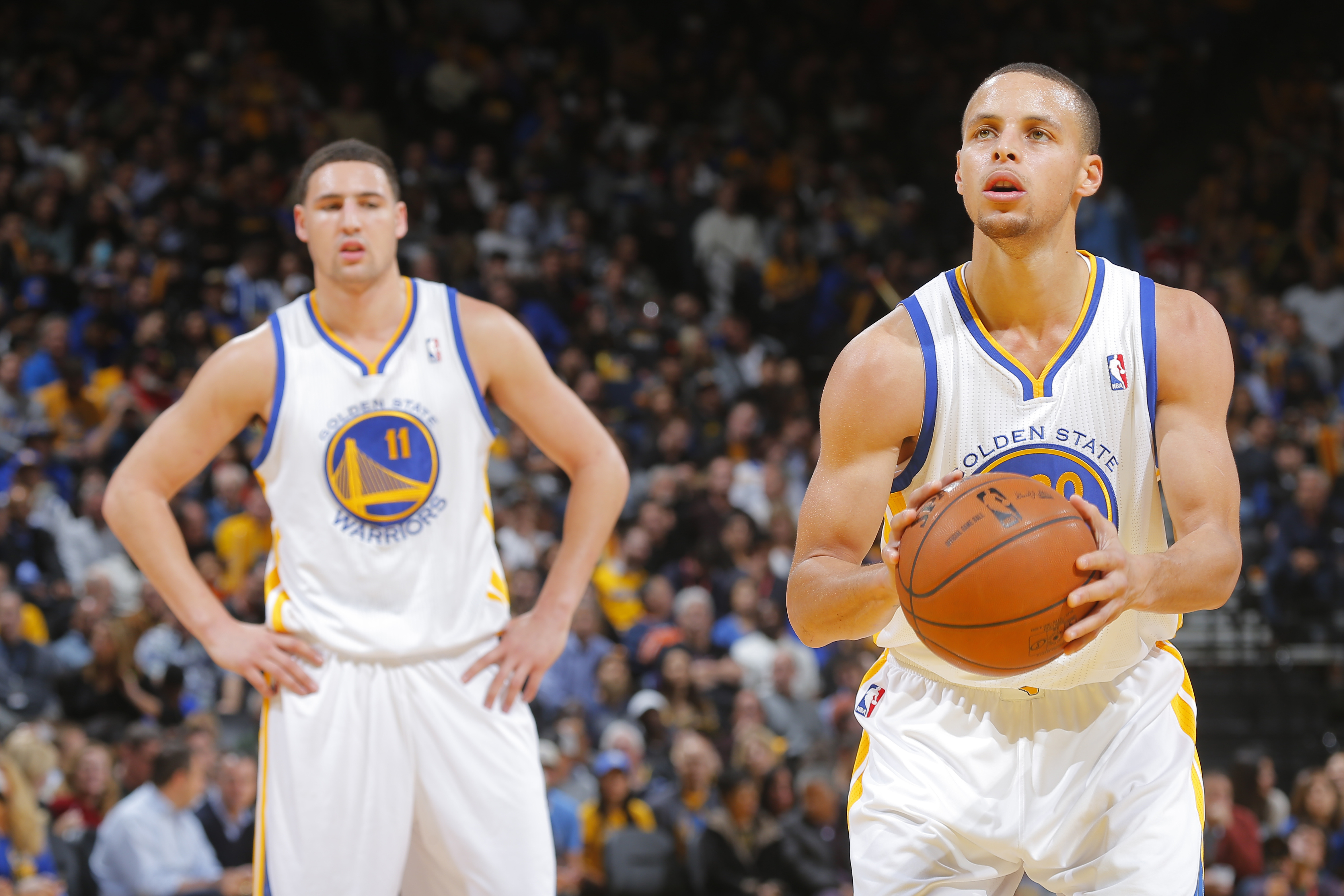 OAKLAND, CA - JANUARY 15: Klay Thompson #11 of the Golden State Warriors watches his teammate Stephen Curry #30 attempt a free throw shot against the Denver Nuggets on January 15, 2014 at Oracle Arena in Oakland, California. NOTE TO USER: User expressly acknowledges and agrees that, by downloading and or using this photograph, user is consenting to the terms and conditions of Getty Images License Agreement. Mandatory Copyright Notice: Copyright 2014 NBAE (Photo by Rocky Widner/NBAE via Getty Images)