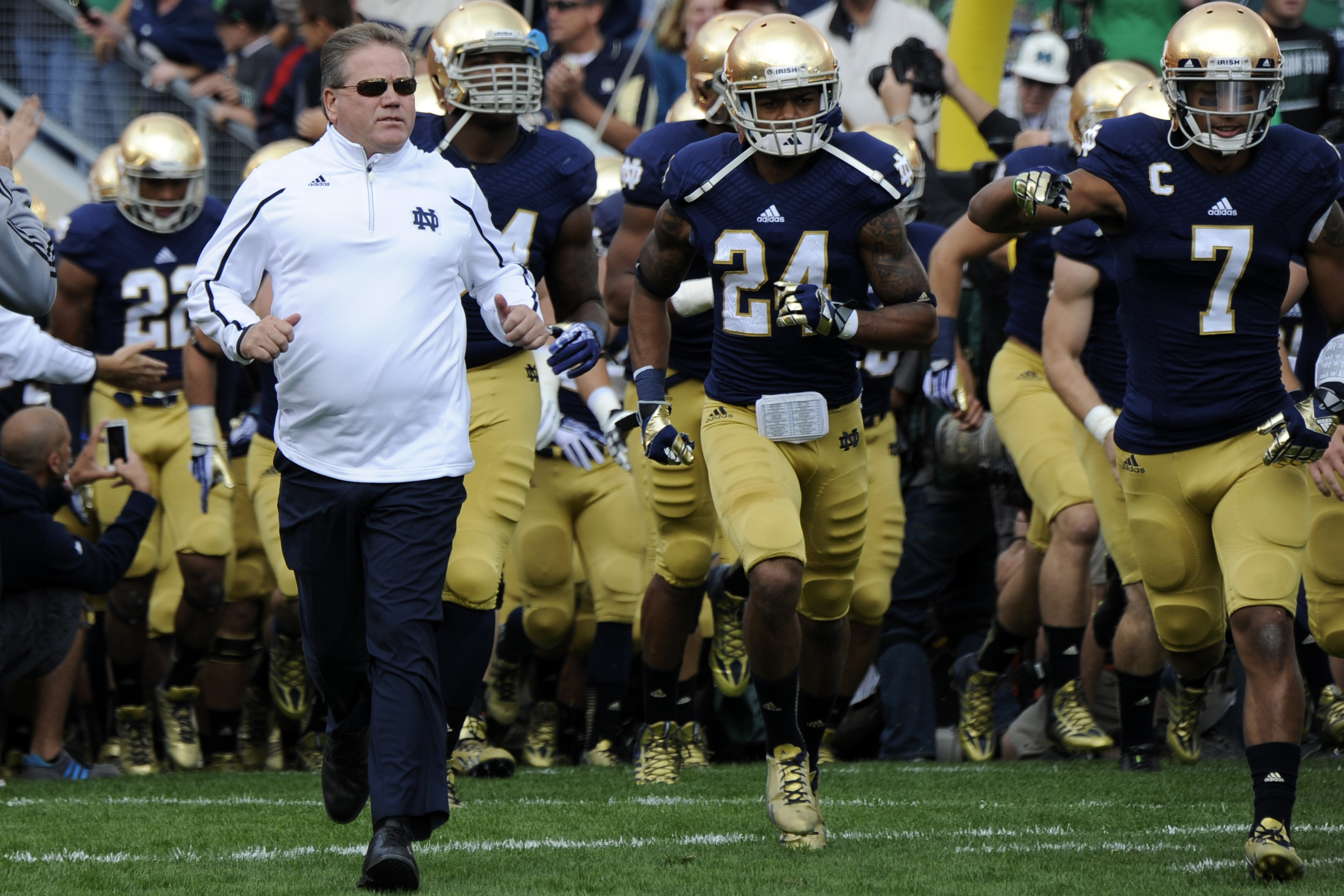 Notre Dame coach Brian Kelly runs onto the field with his team  prior to a in a NCAA college football game with Michigan State Saturday Sept. 21, 2013 in South Bend, Ind. (AP Photo/Joe Raymond)