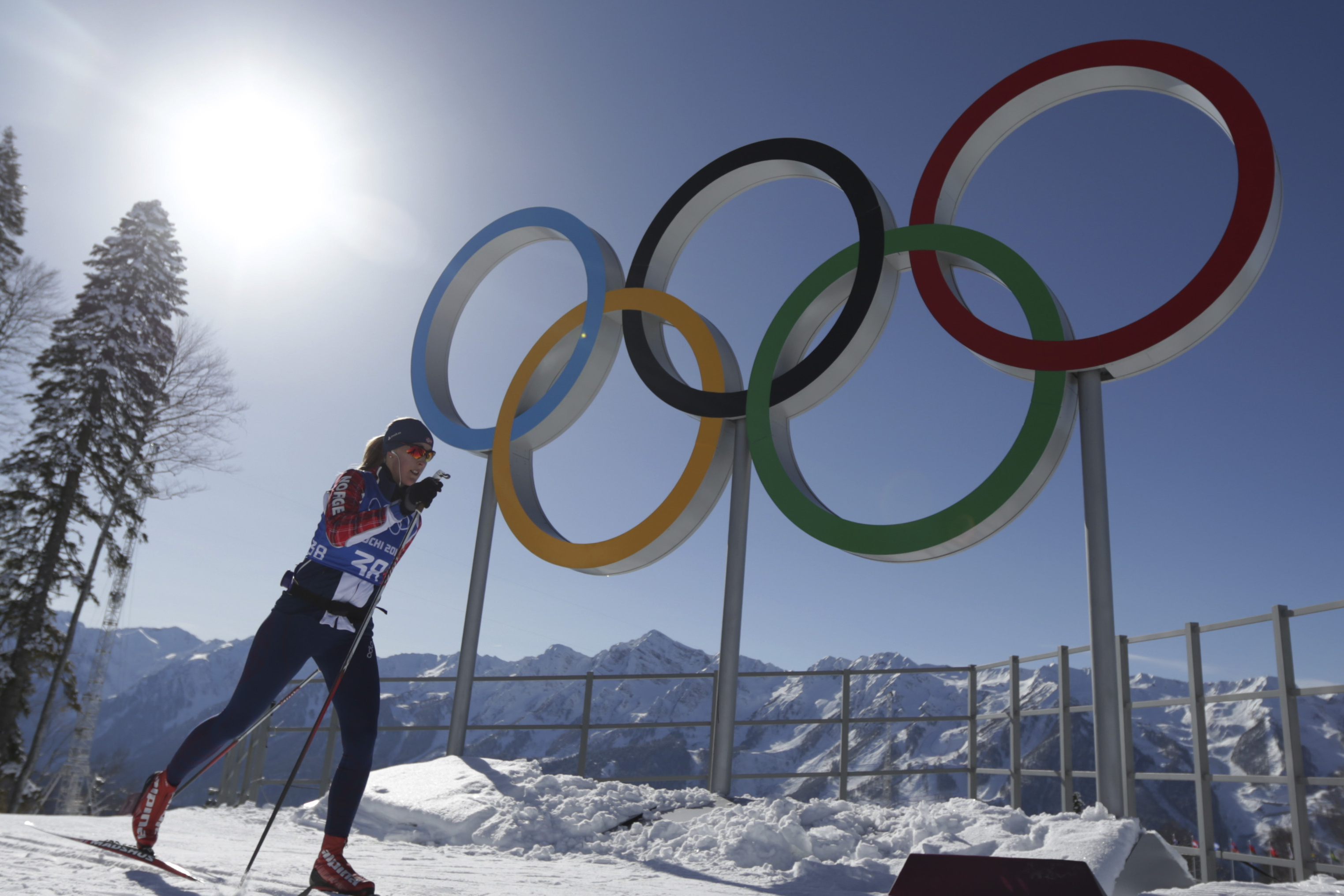 An unidentified athlete passes by the Olympic rings in the Cross Country stadium prior to the 2014 Winter Olympics, Tuesday, Feb. 4, 2014, in Krasnaya Polyana, Russia. (AP Photo/Matthias Schrader)