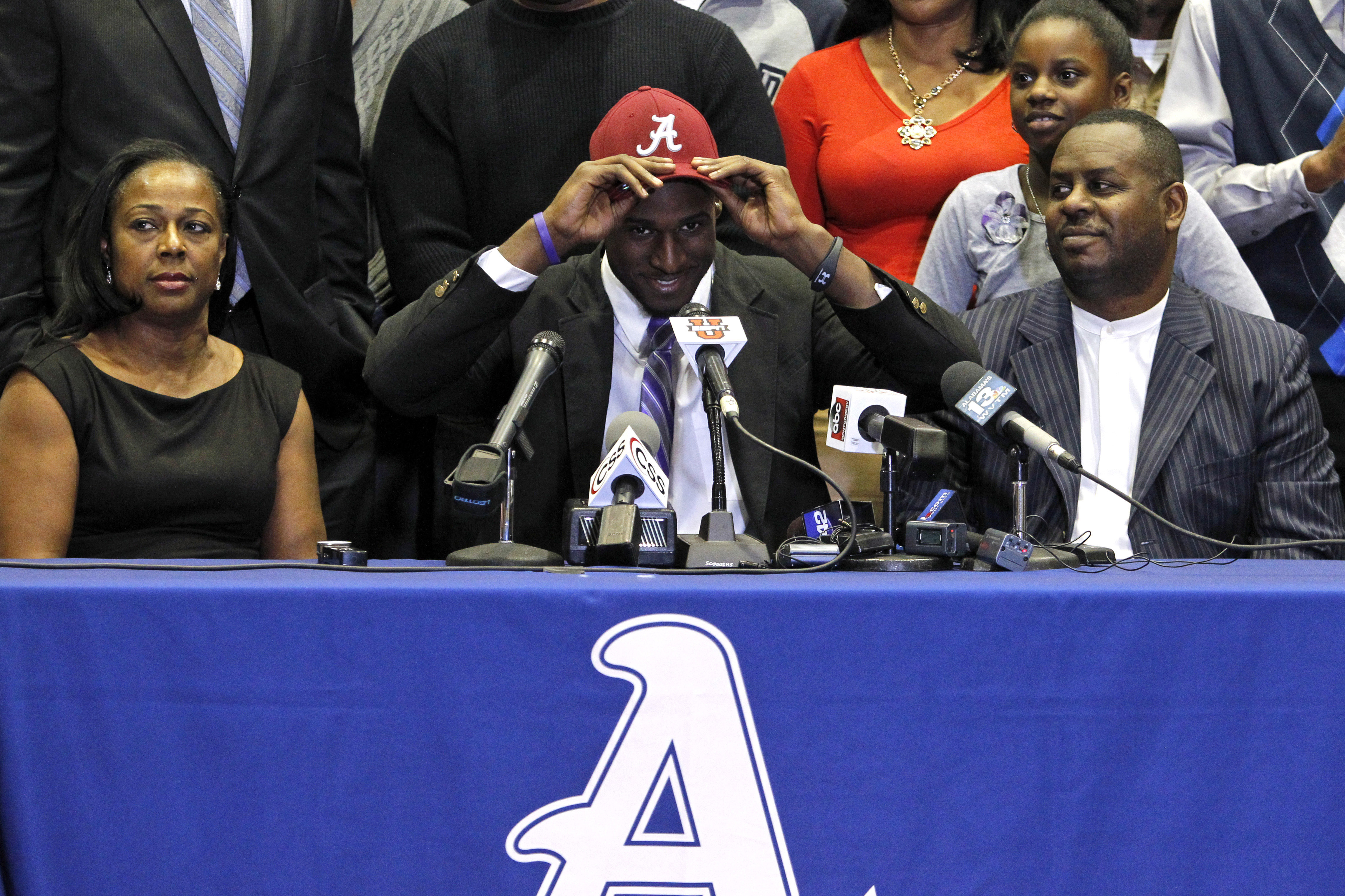 Chenavis Evans, left, and d Allan Evans, right, watch as their son Rashaan Evans dons an Alabama hat as the Auburn High School football player announces that he will attend Alabama during a national signing day ceremony on Wednesday, Feb. 5, 2014, in Auburn, Ala. (AP Photo/Butch Dill)